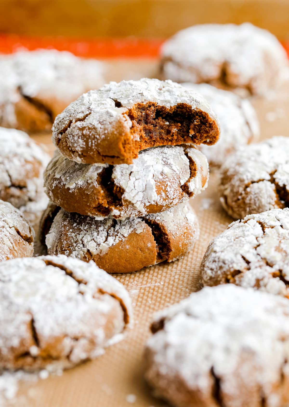 stack of 3 brown cookies with powdered sugar, on silicone mat.