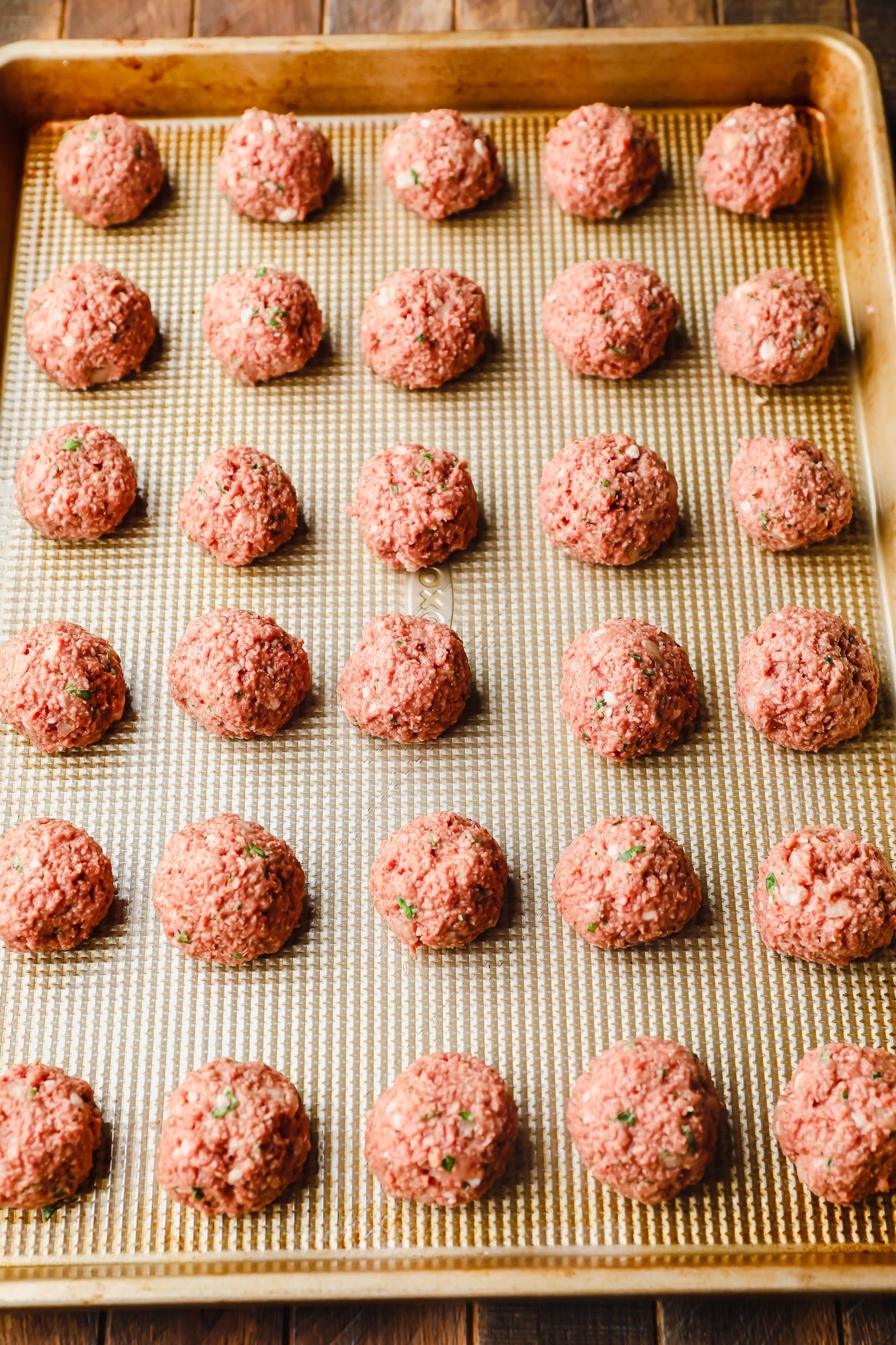 rolled vegan meatballs in rows on a baking sheet.