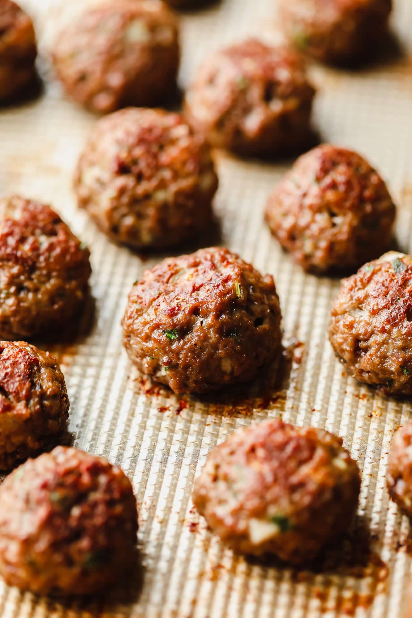 close up on rows of baked vegan meatballs on a baking sheet.