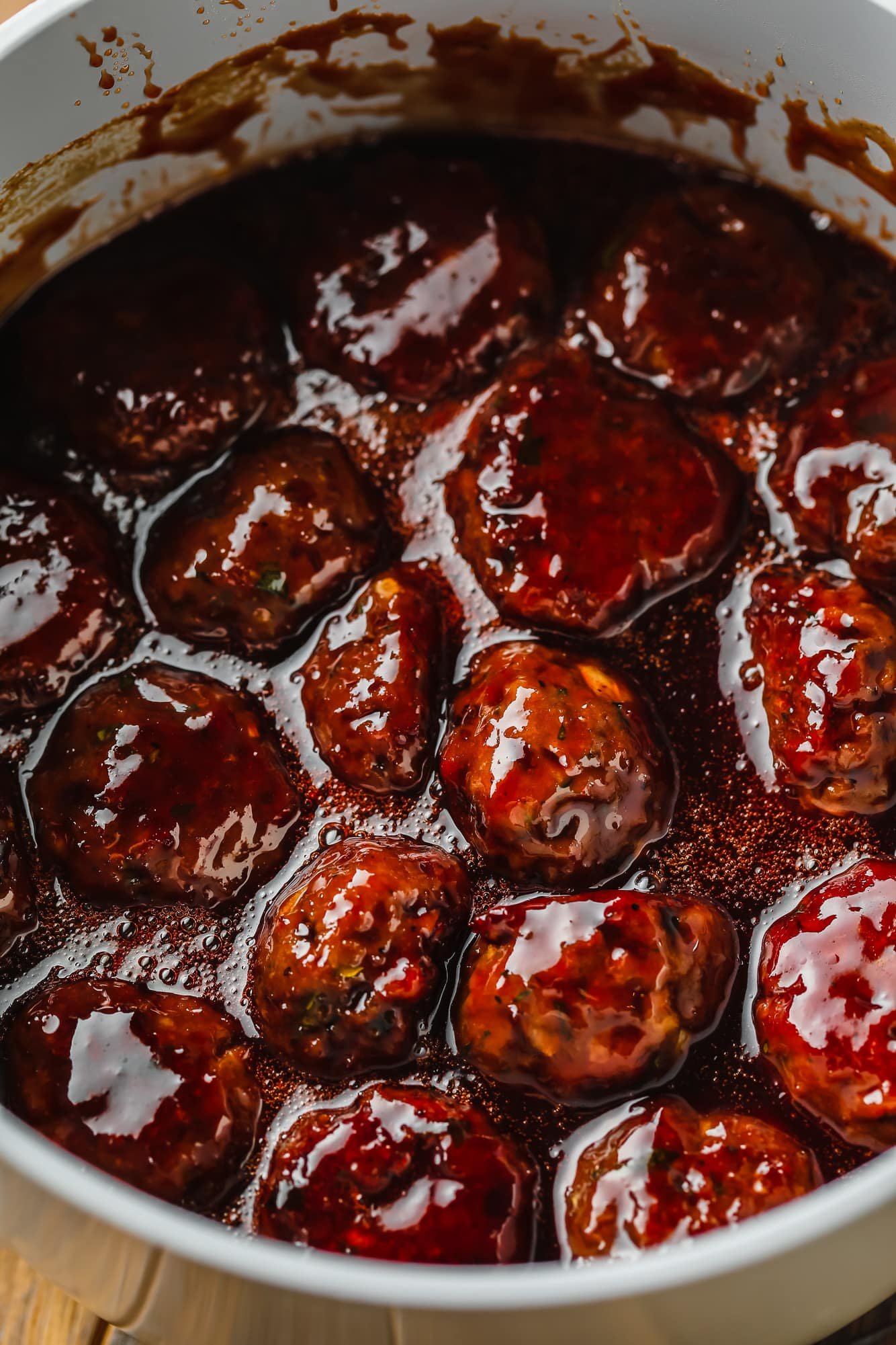 vegan meatballs in a saucepan with BBQ sauce and grape jelly.