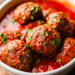 vegan meatballs covered in marinara sauce in a white bowl.