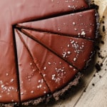 close up on a sliced vegan chocolate tart topped with flake salt.