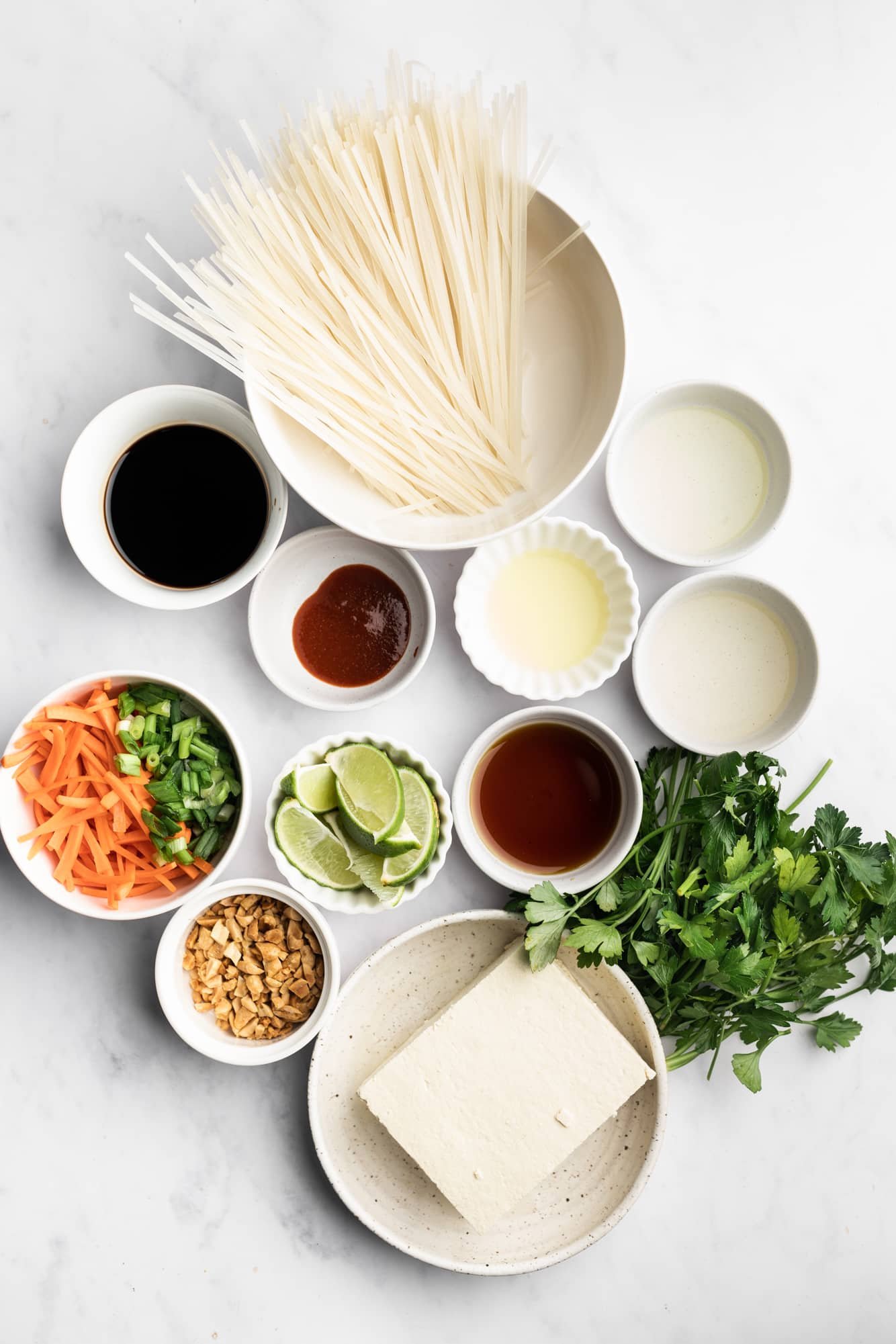 ingredients for vegan pad thai in individual white bowls.