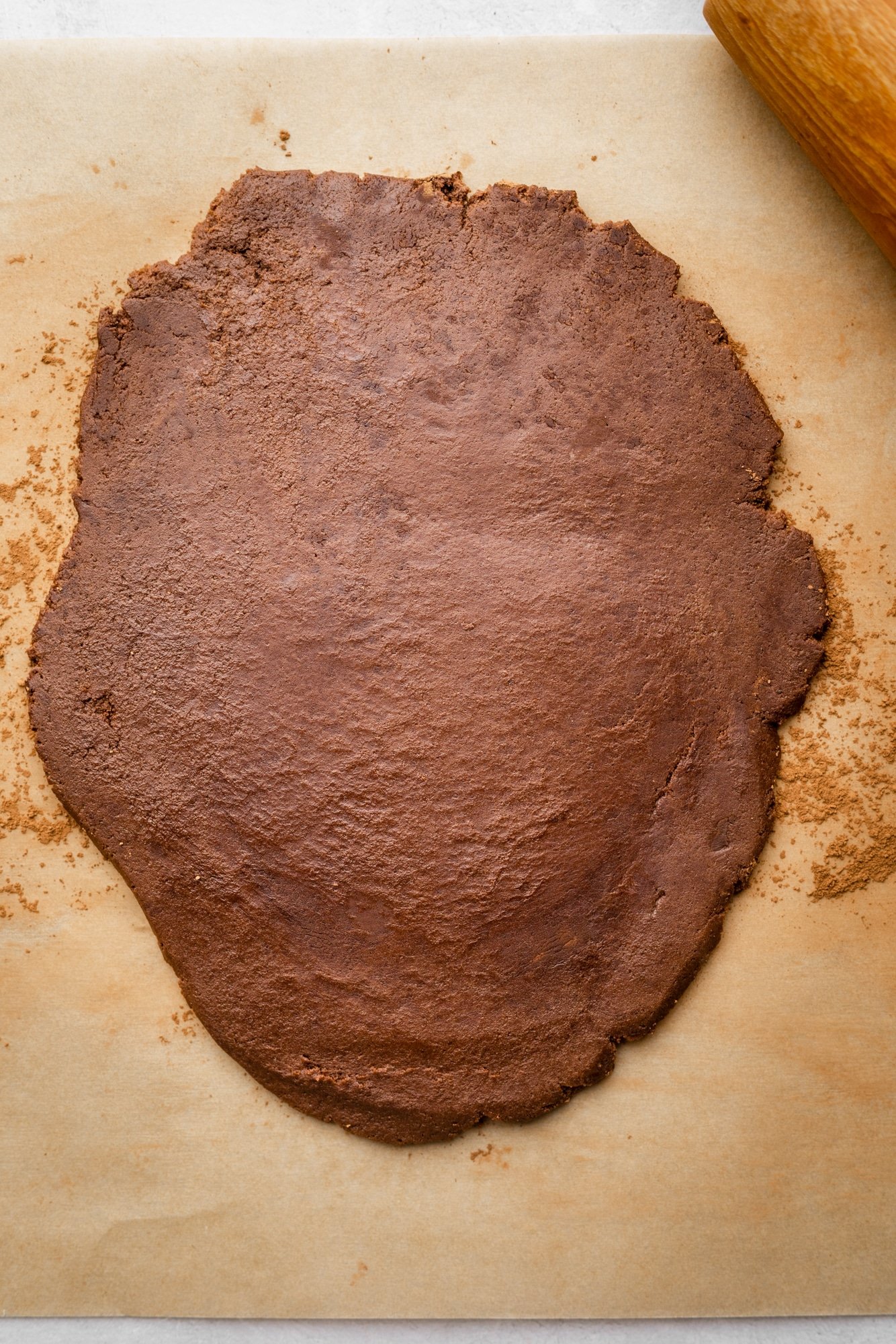 chocolate cookie dough rolled out into a flat layer on a parchment-lined surface.
