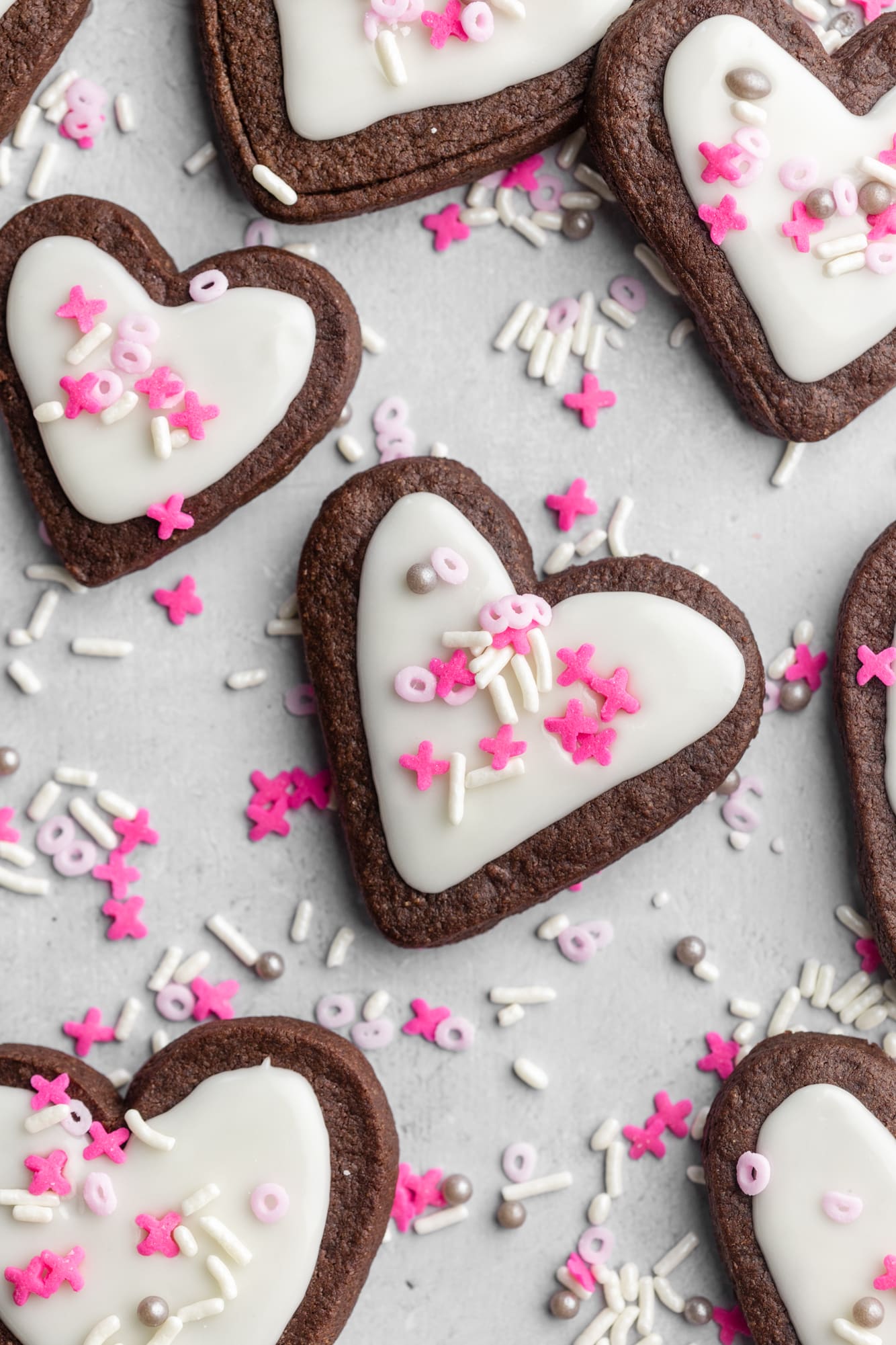 heart-shaped chocolate sugar cookies decorated with white icing and pink sprinkles.