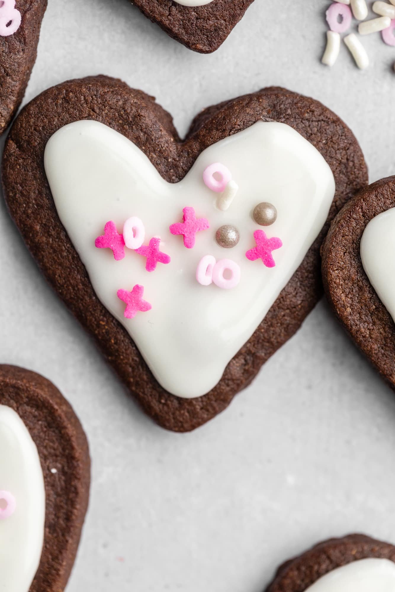 heart-shaped chocolate sugar cookies decorated with white icing and pink sprinkles.