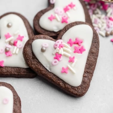 heart-shaped chocolate sugar cookies decorated with white icing and pink sprinkles.