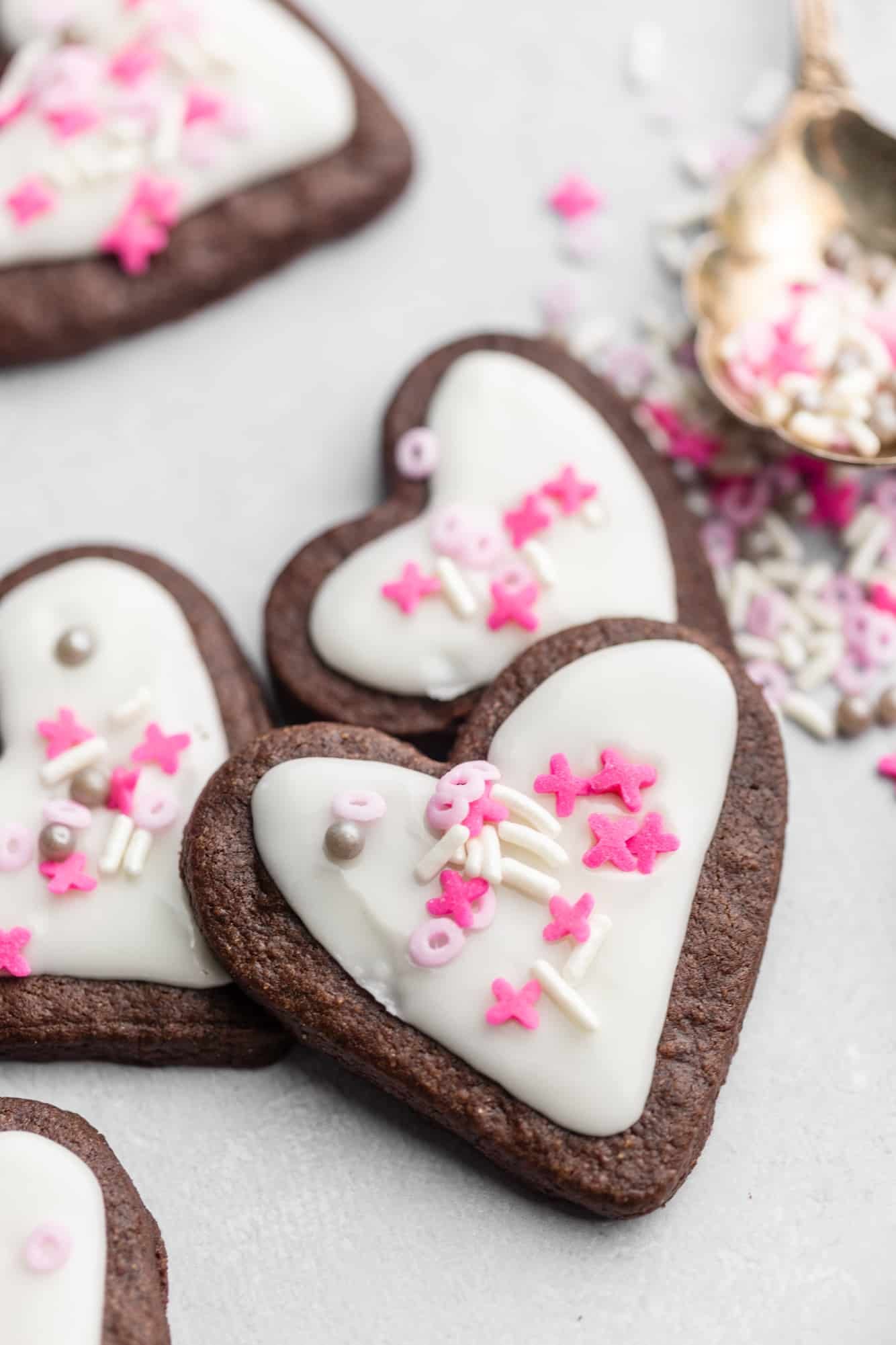 heart-shaped chocolate sugar cookies decorated with white icing and pink sprinkles.