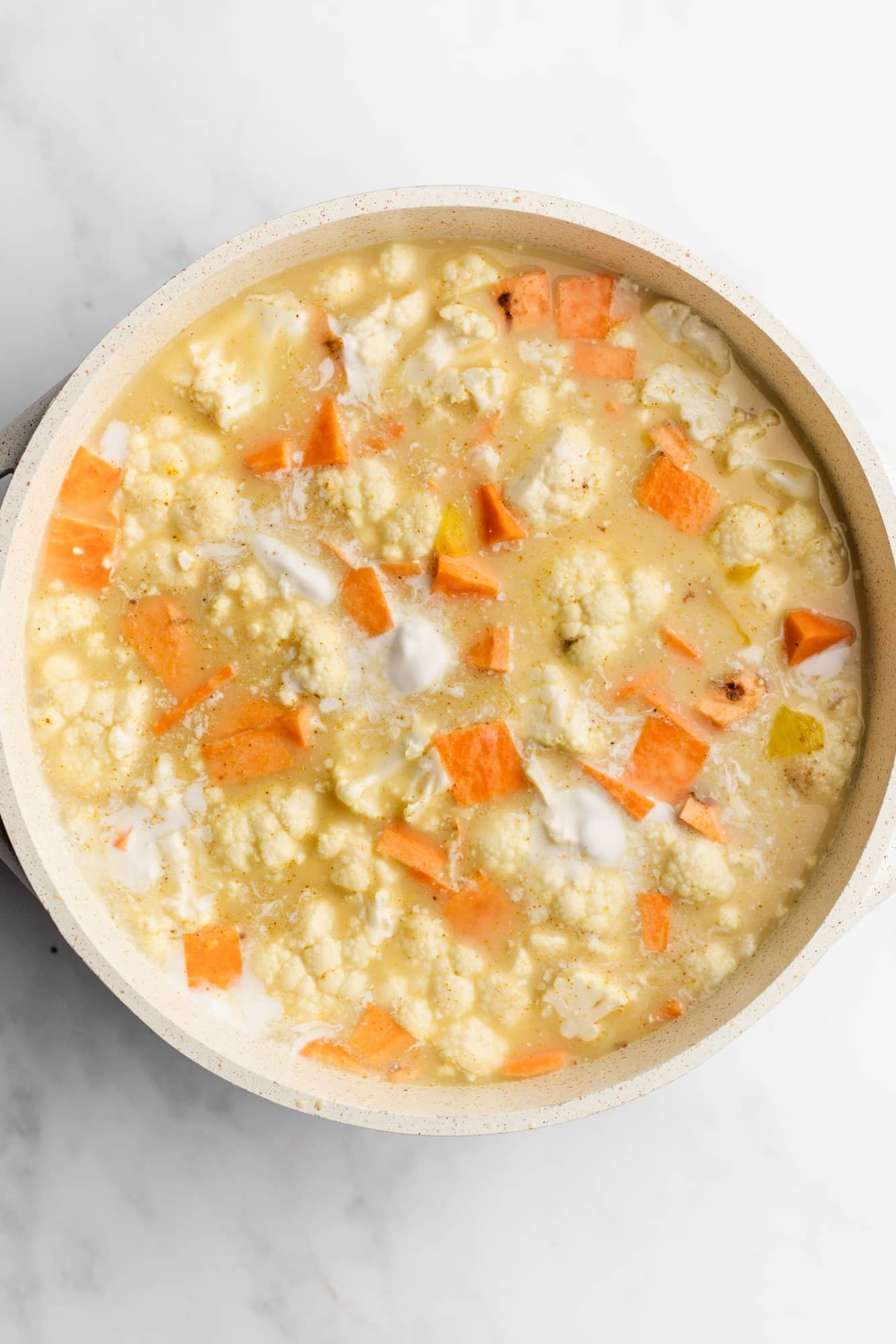 cooking coconut curry lentil soup in a large white pot.