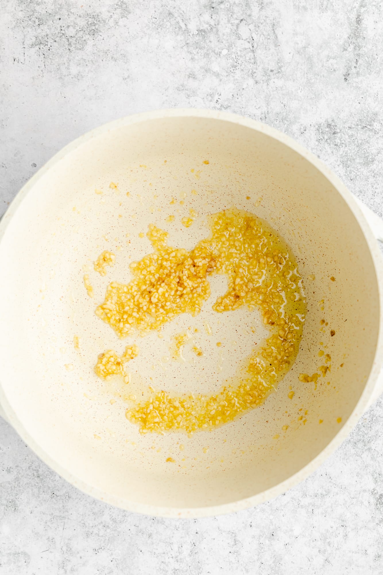 sauteeing garlic and ginger in an oiled white pot.