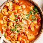 Italian chickpea soup topped with vegan parmesan and parsley in a bowl.