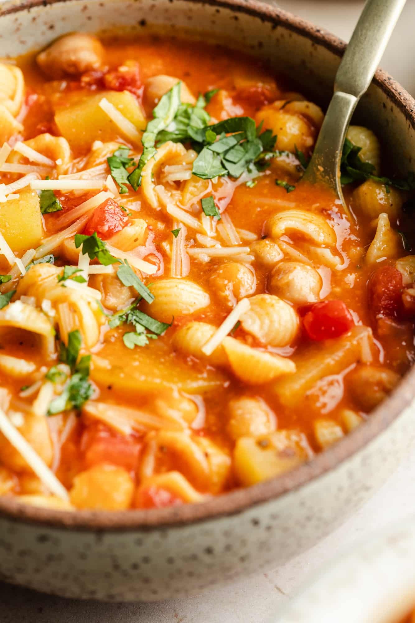 close up on Italian chickpea soup topped with vegan parmesan and parsley in a bowl.