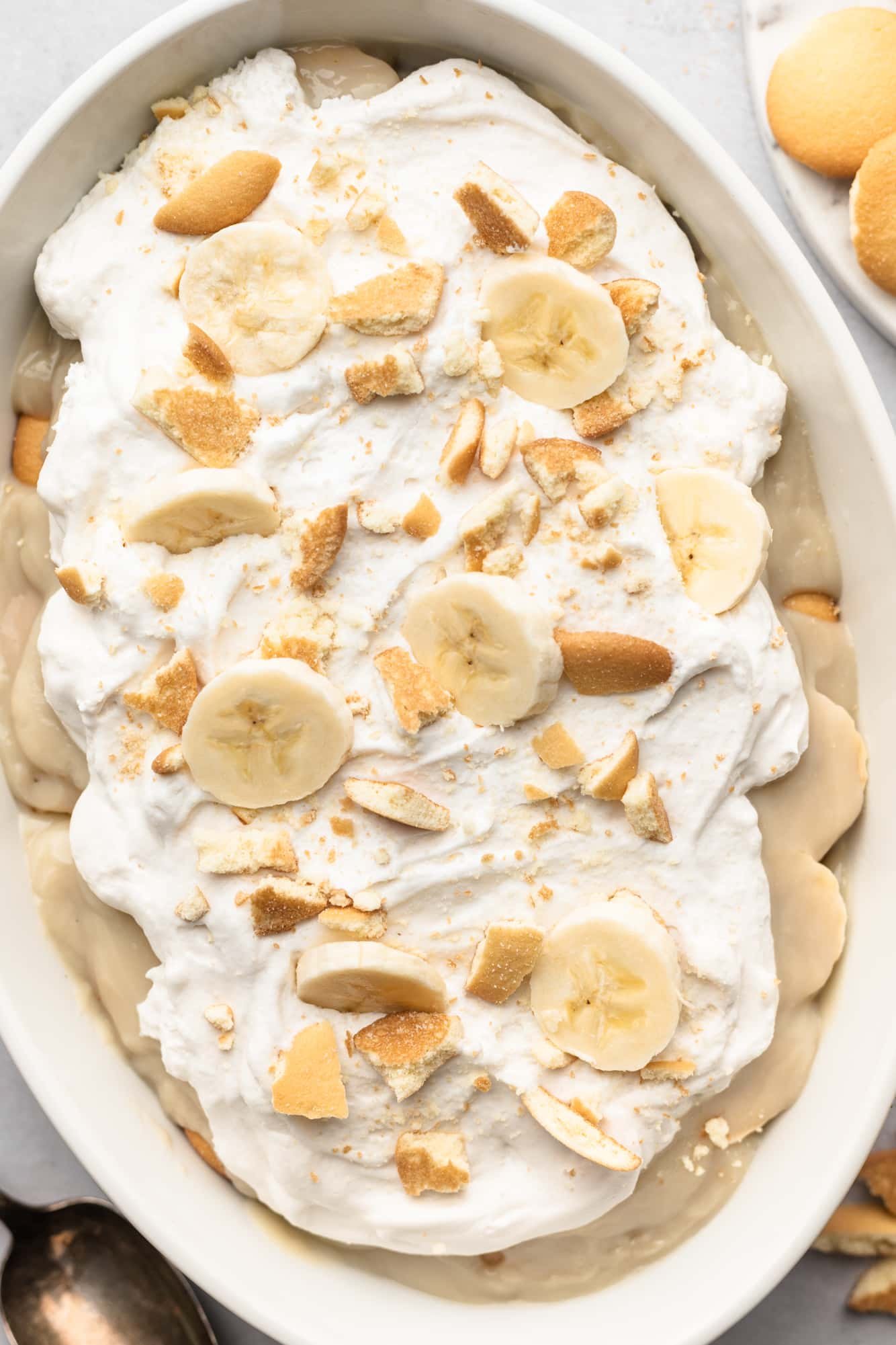 assembled vegan banana pudding topped with whipped cream, crushed cookies, and banana slices.