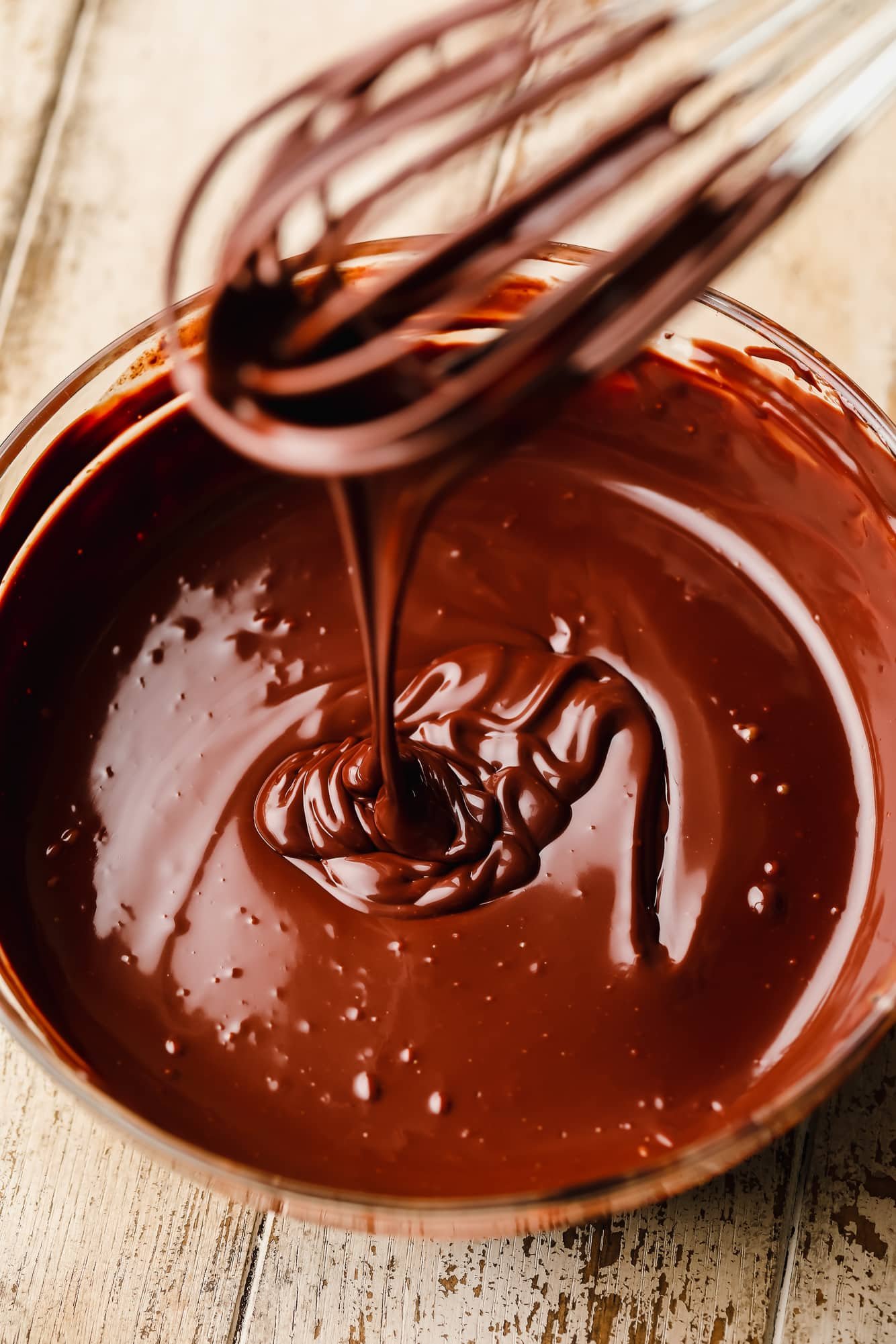 whisking chocolate ganache in a glass bowl.