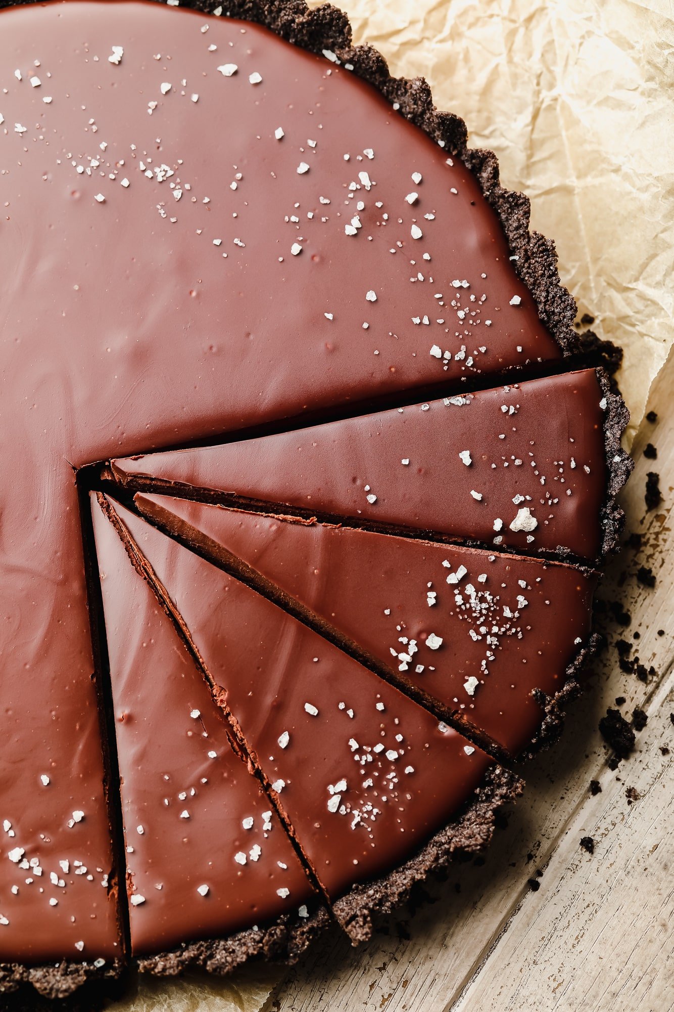 close up on a sliced vegan chocolate tart topped with flake salt.