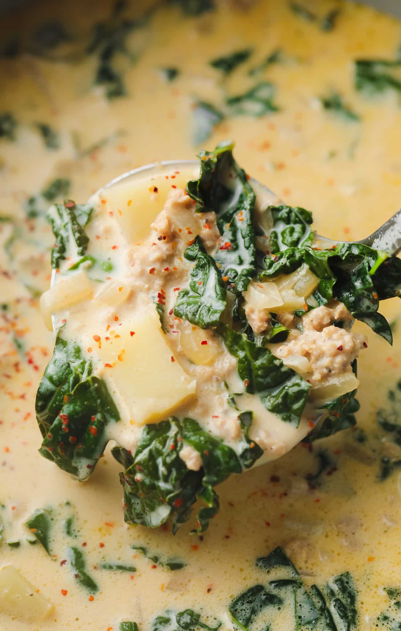 a soup ladle full of cooked vegan zuppa toscana soup.