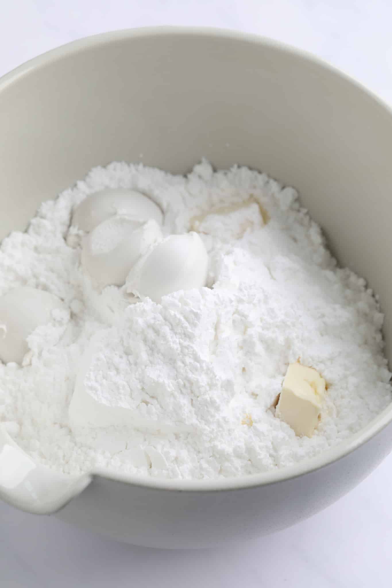 powdered sugar, coconut milk, and butter in a large white bowl.
