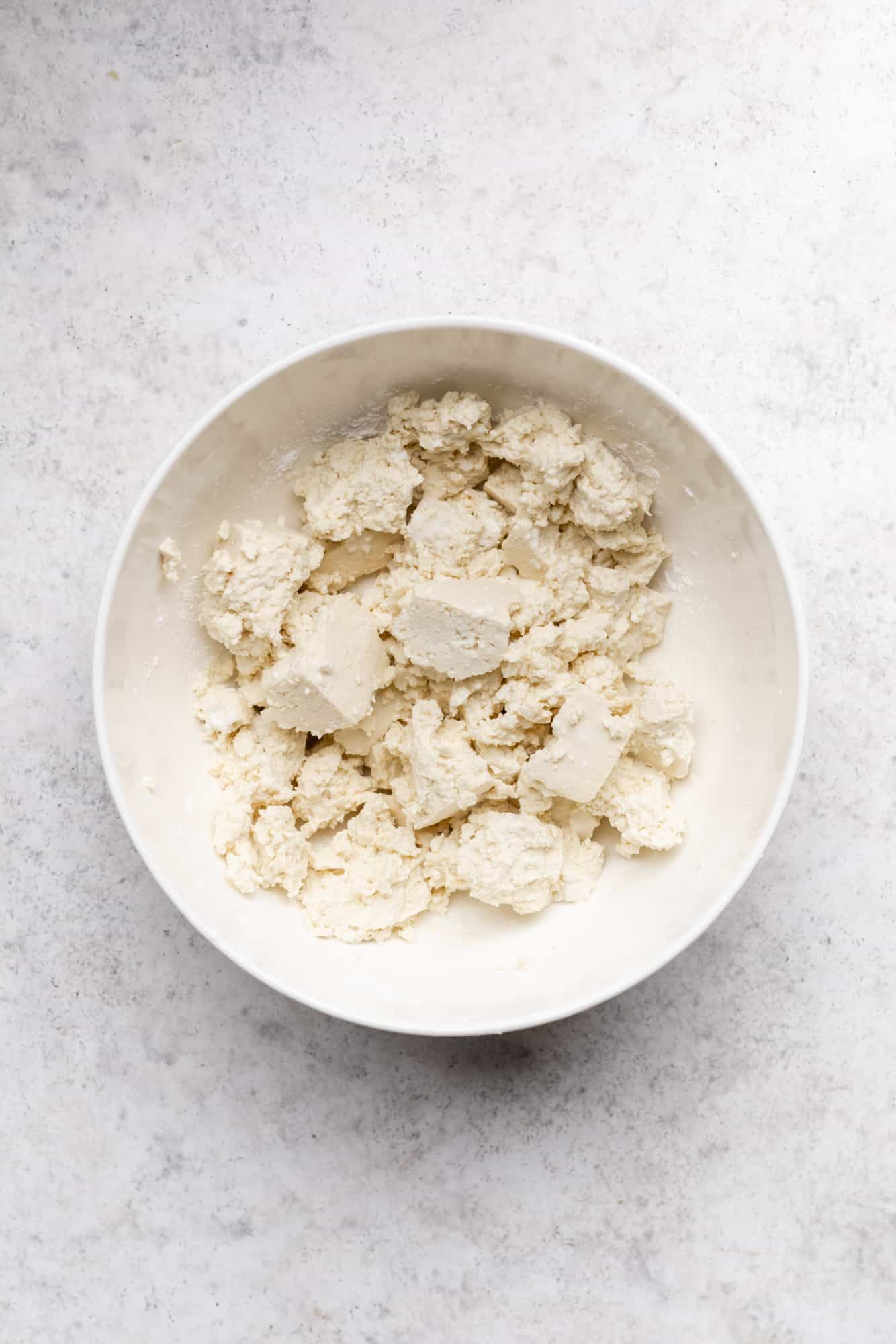 ripped tofu chunks in a white bowl.