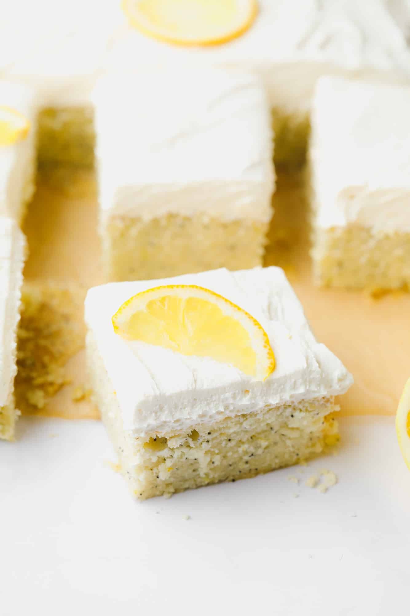 a slice of lemon poppyseed cake topped with a lemon slice cut from a larger cake.