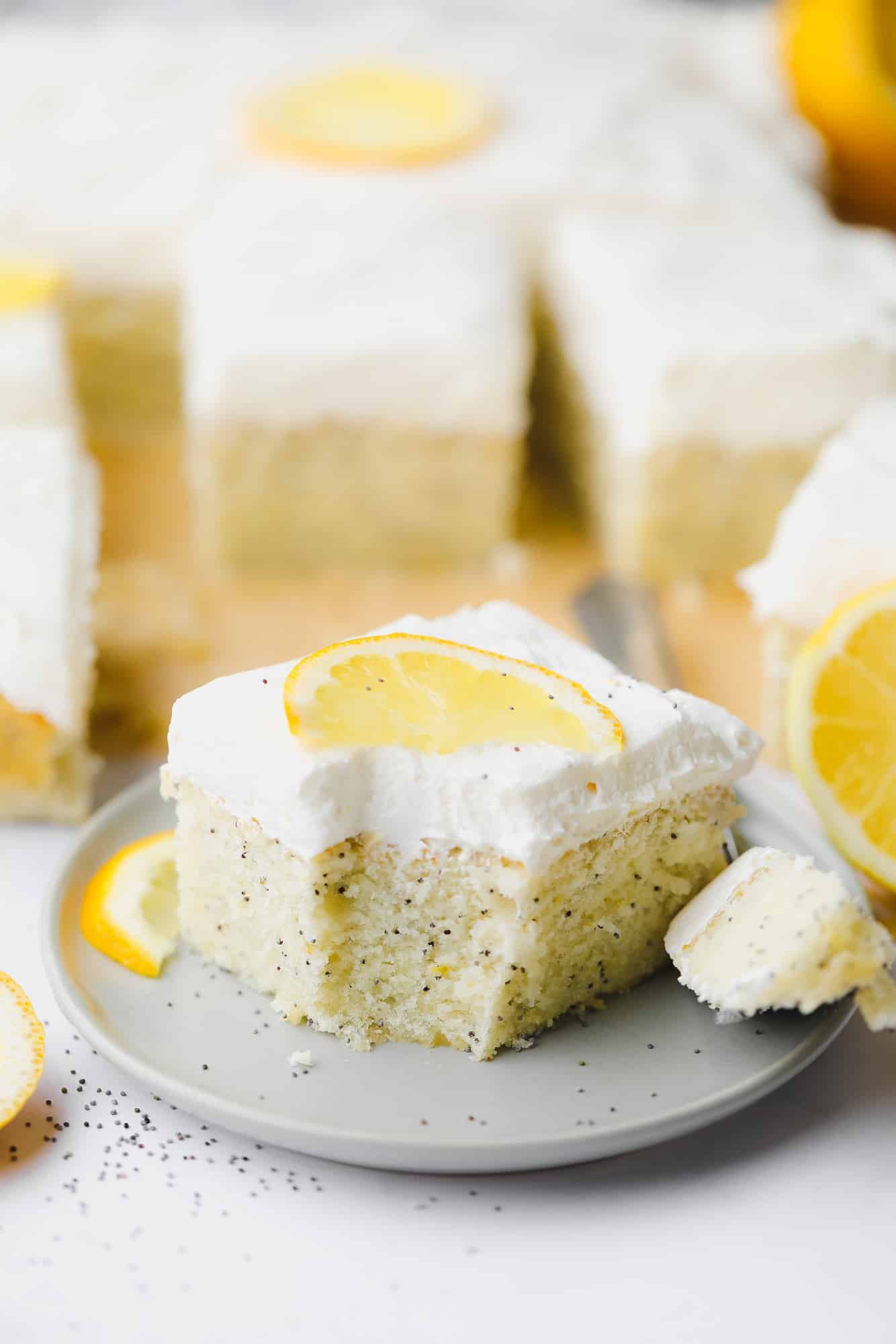 a piece of vegan lemon poppyseed cake with a bite removed on a small grey plate.