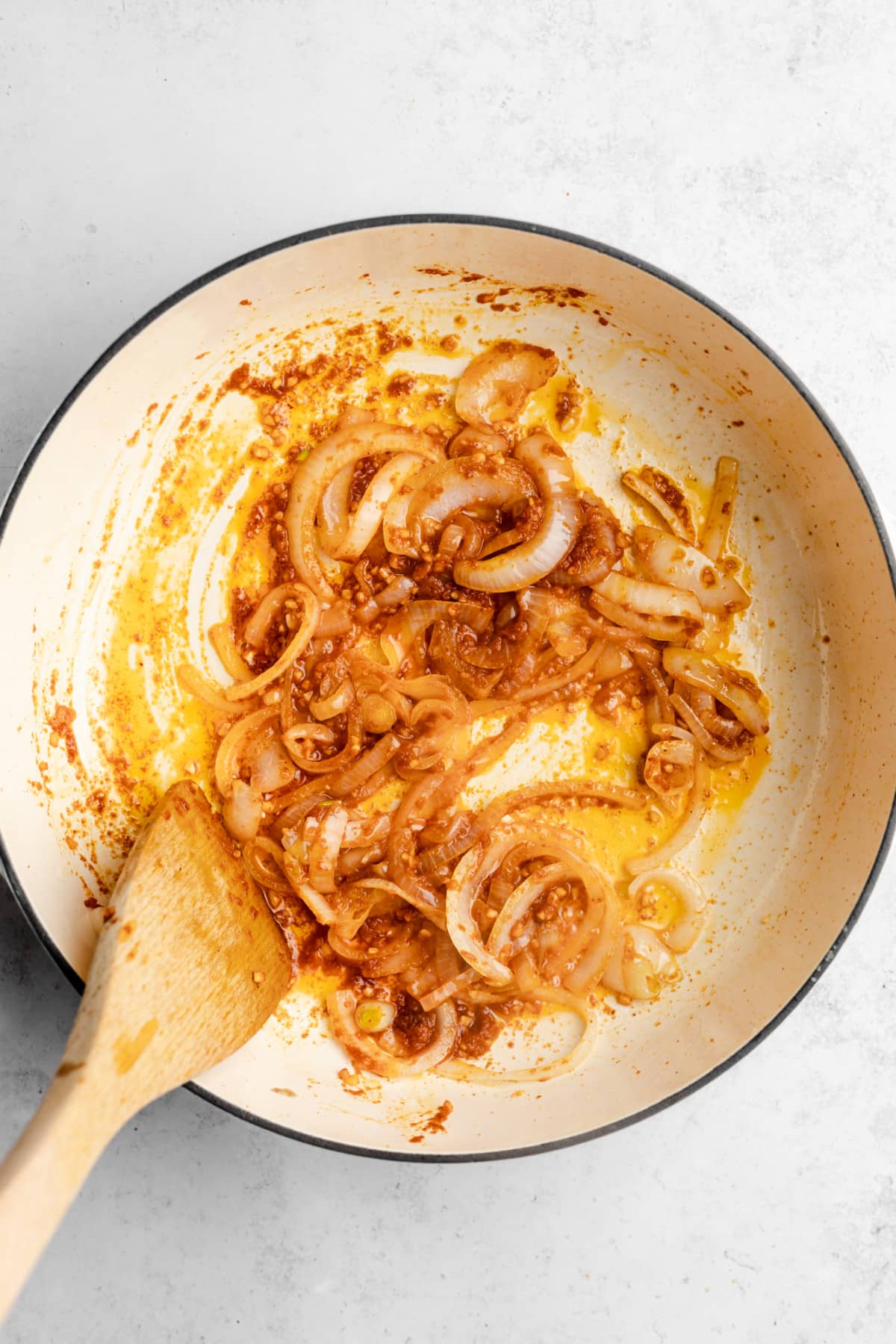 onions and garlic being stir fried in a pot with a wooden spoon