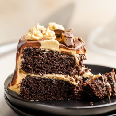 close up on a slice of chocolate peanut butter cake on a black plate.