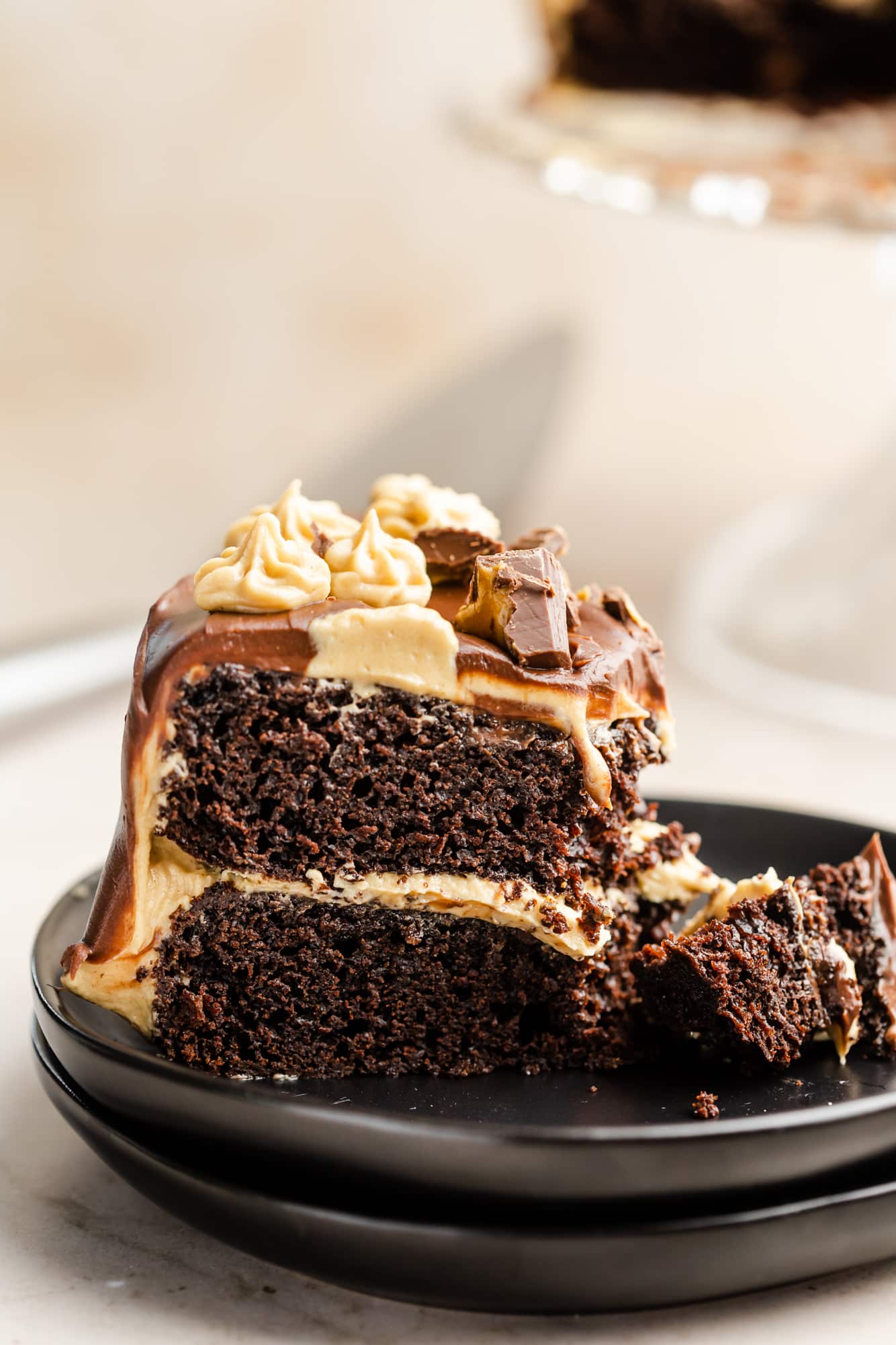 close up on a slice of chocolate peanut butter cake on a black plate.