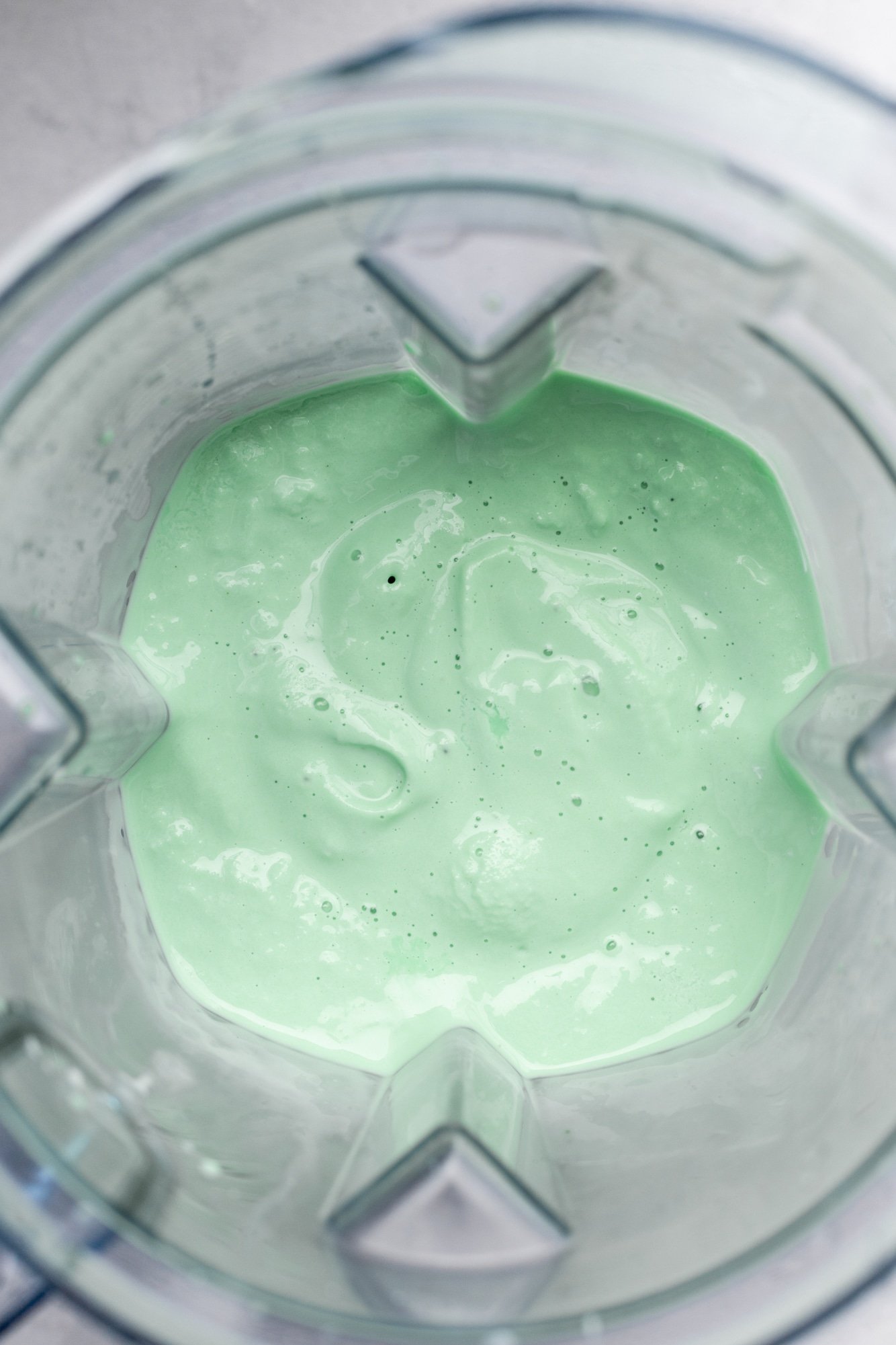 a blended mint green vegan shamrock shake in a blender.
