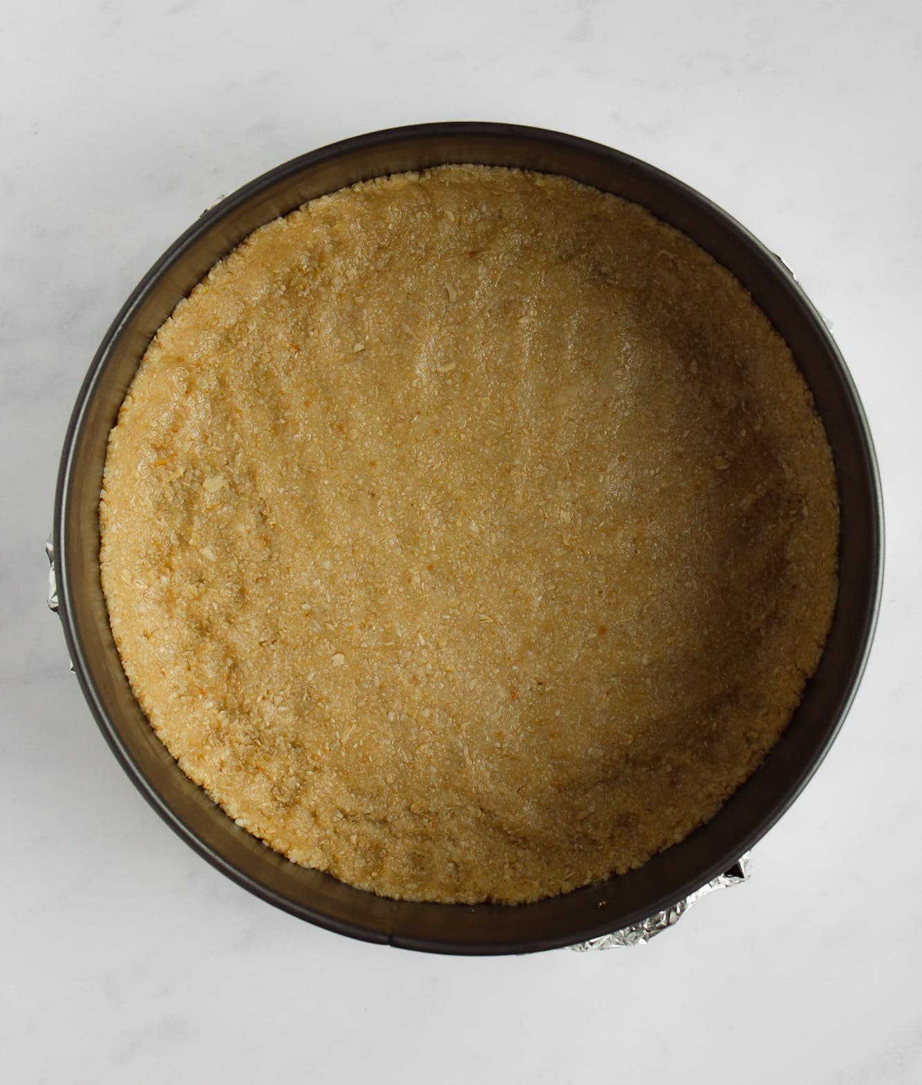almond oat cheesecake crust pressed into a springform pan.