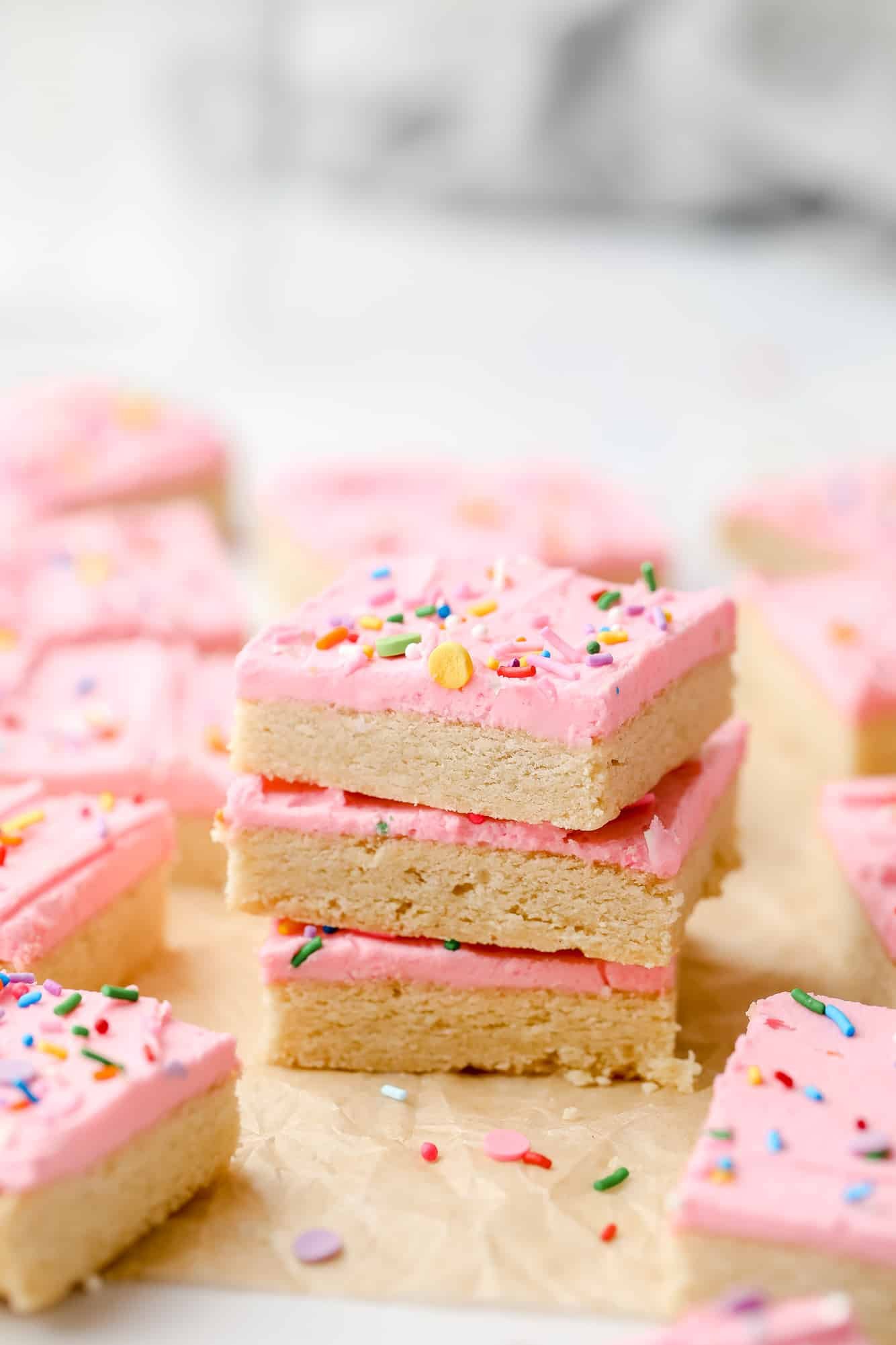 a stack of 3 sugar cookie bars decorated with pink frosting on top of each other.