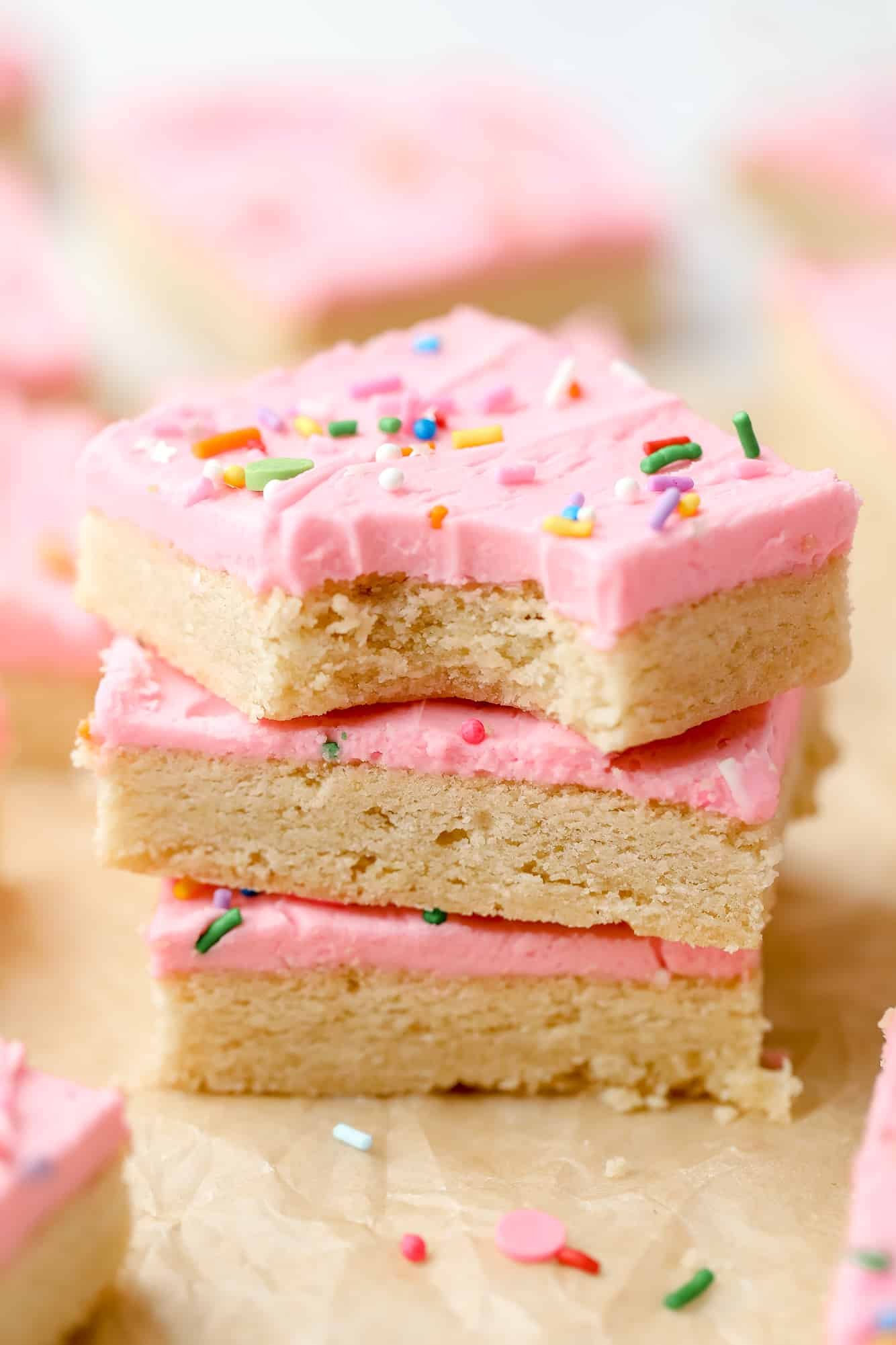 a stack of 3 sugar cookie bars decorated with pink frosting on top of each other.