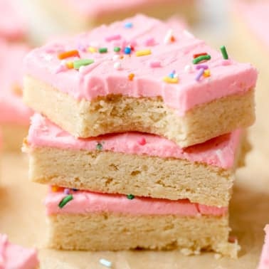 a stack of 3 sugar cookie bars decorated with pink frosting on top of each other.