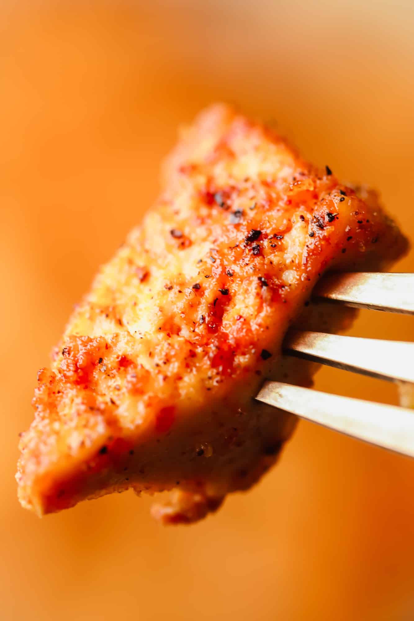 close up on a piece of crispy baked tofu on a metal fork.