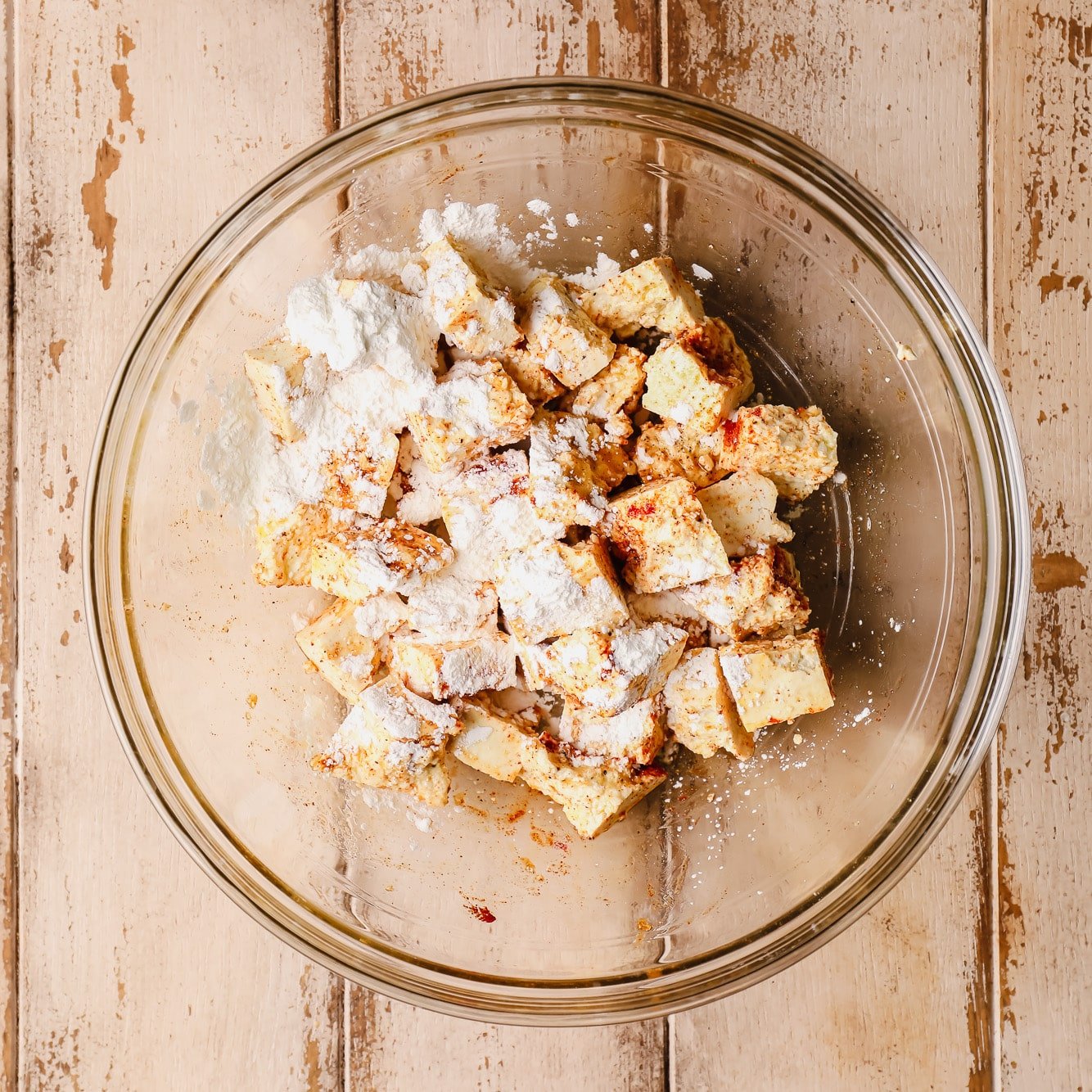 tofu pieces covered in cornstarch in a glass bowl.