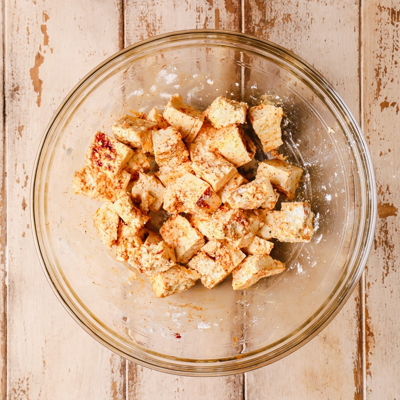 seasoned raw tofu pieces in a glass bowl.