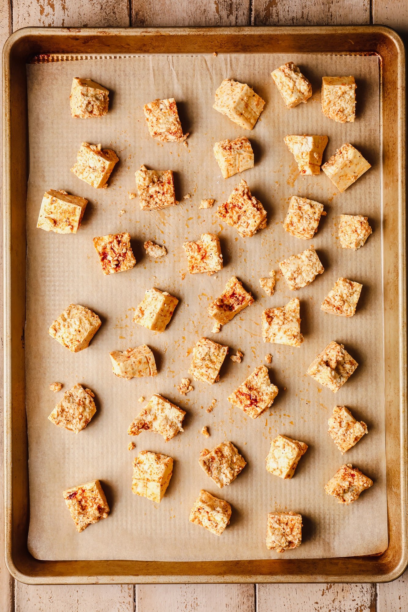 seasoned raw tofu pieces in rows on a baking sheet.