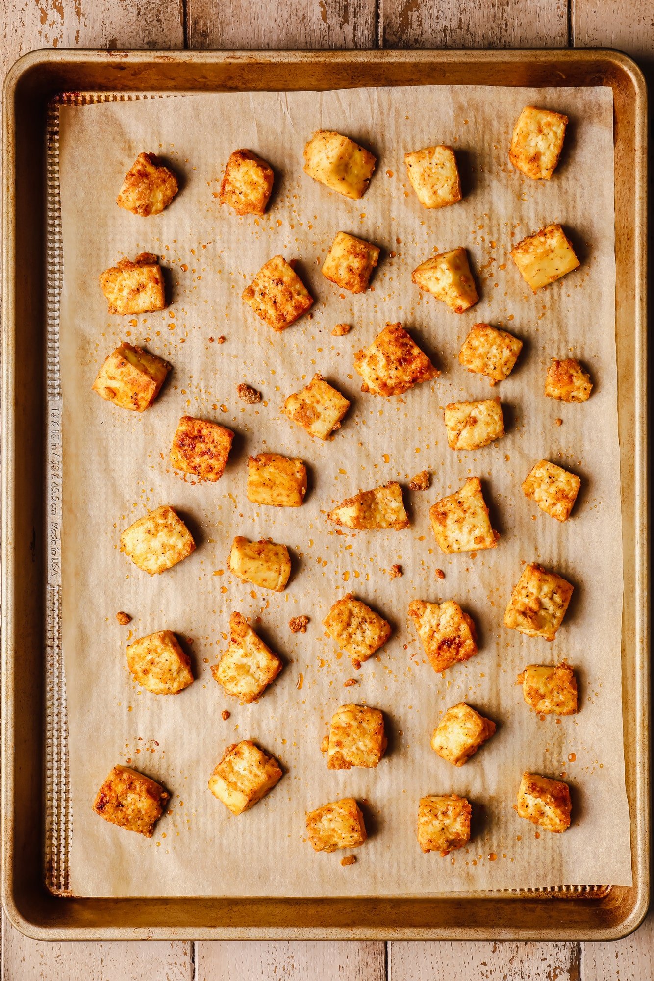 baked tofu pieces in rows on a baking sheet.