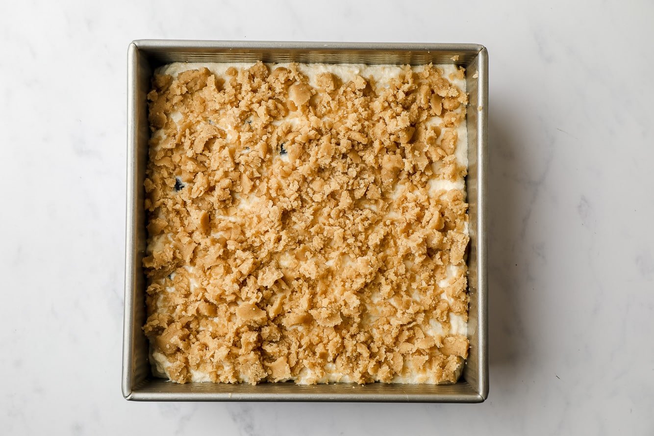 unbaked coffee cake topped with streusel in a square cake pan.