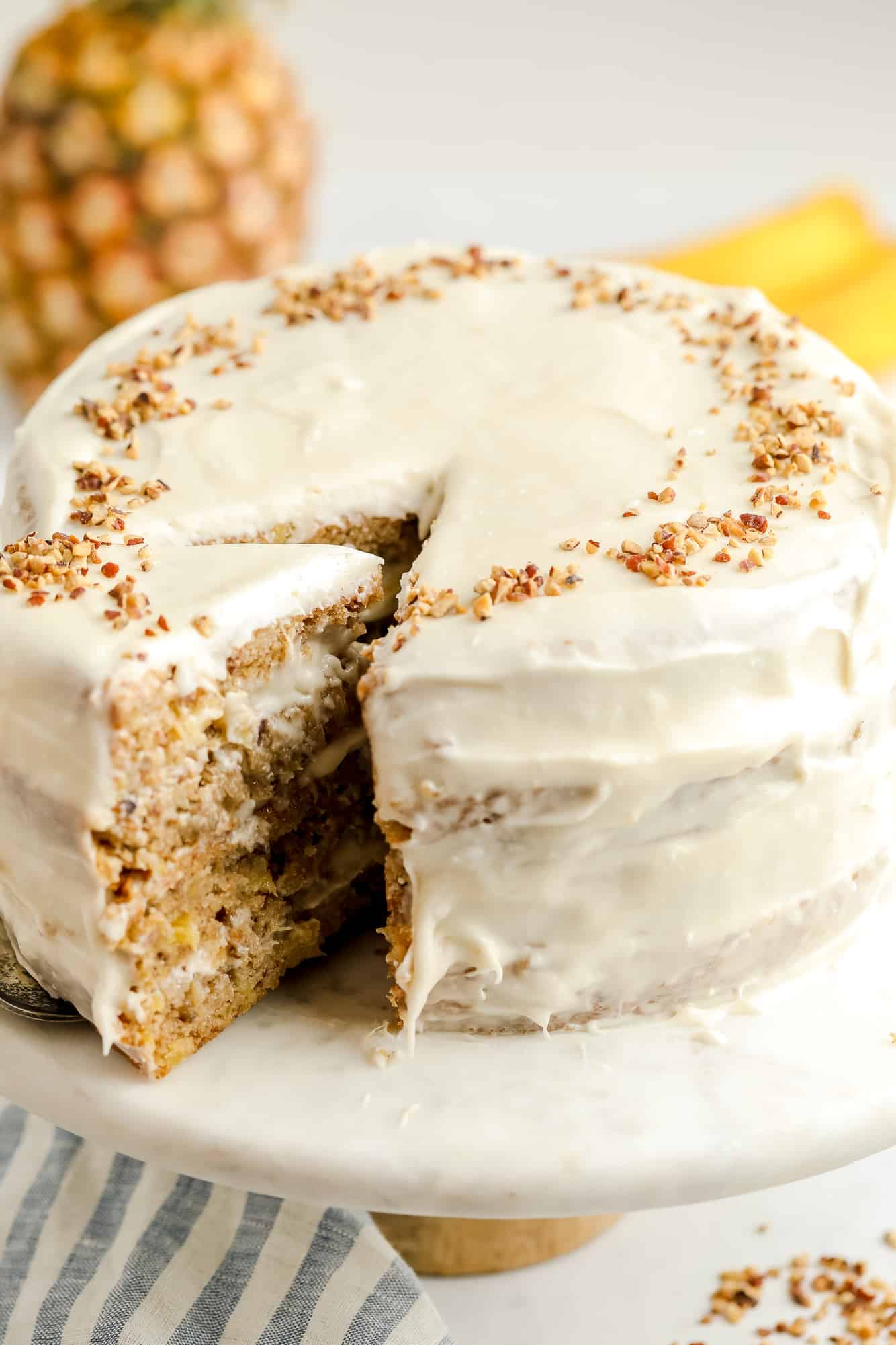 a cream cheese frosted-vegan hummingbird cake with a slice being removed.