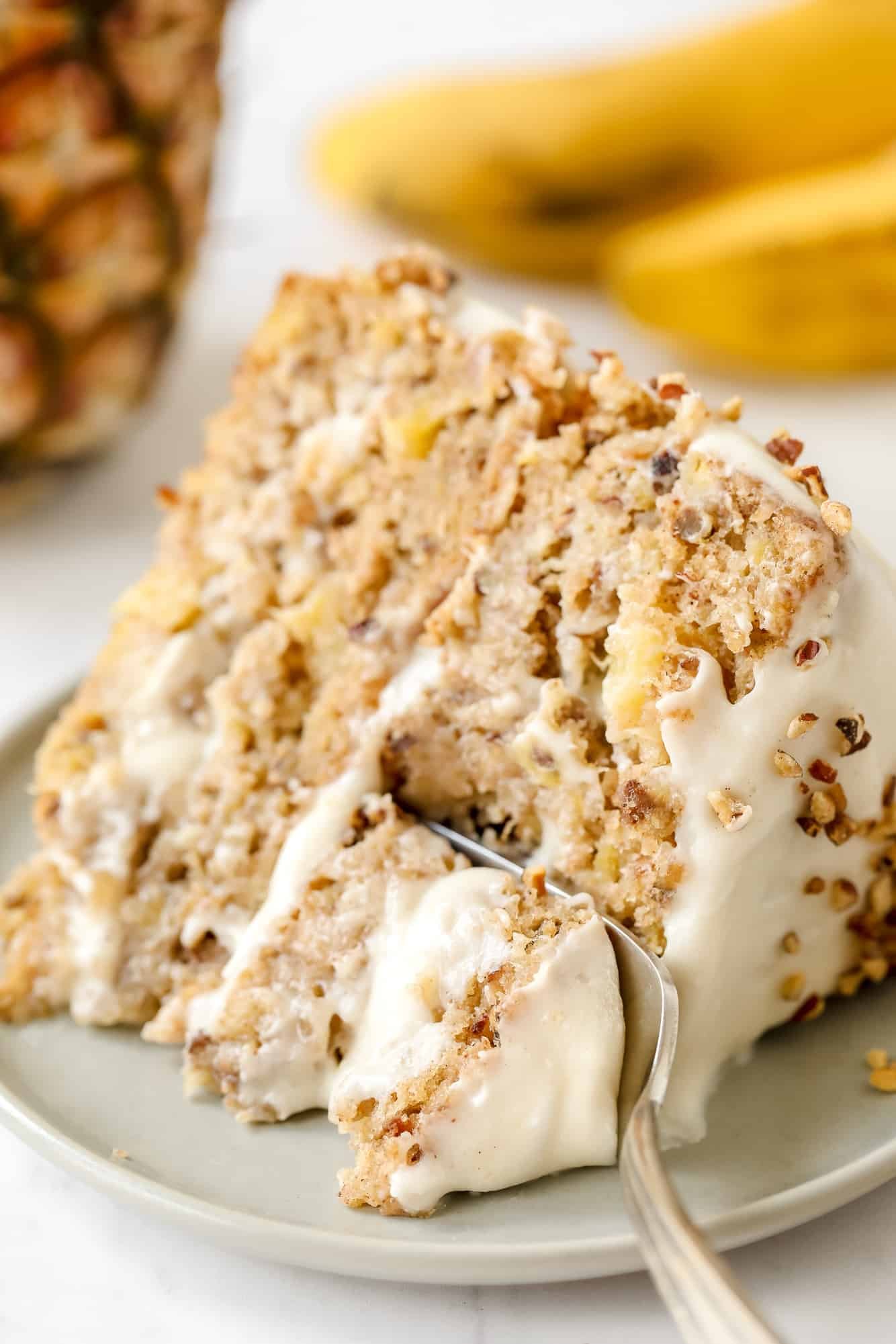 using a fork to take a bite from a slice of vegan hummingbird cake.