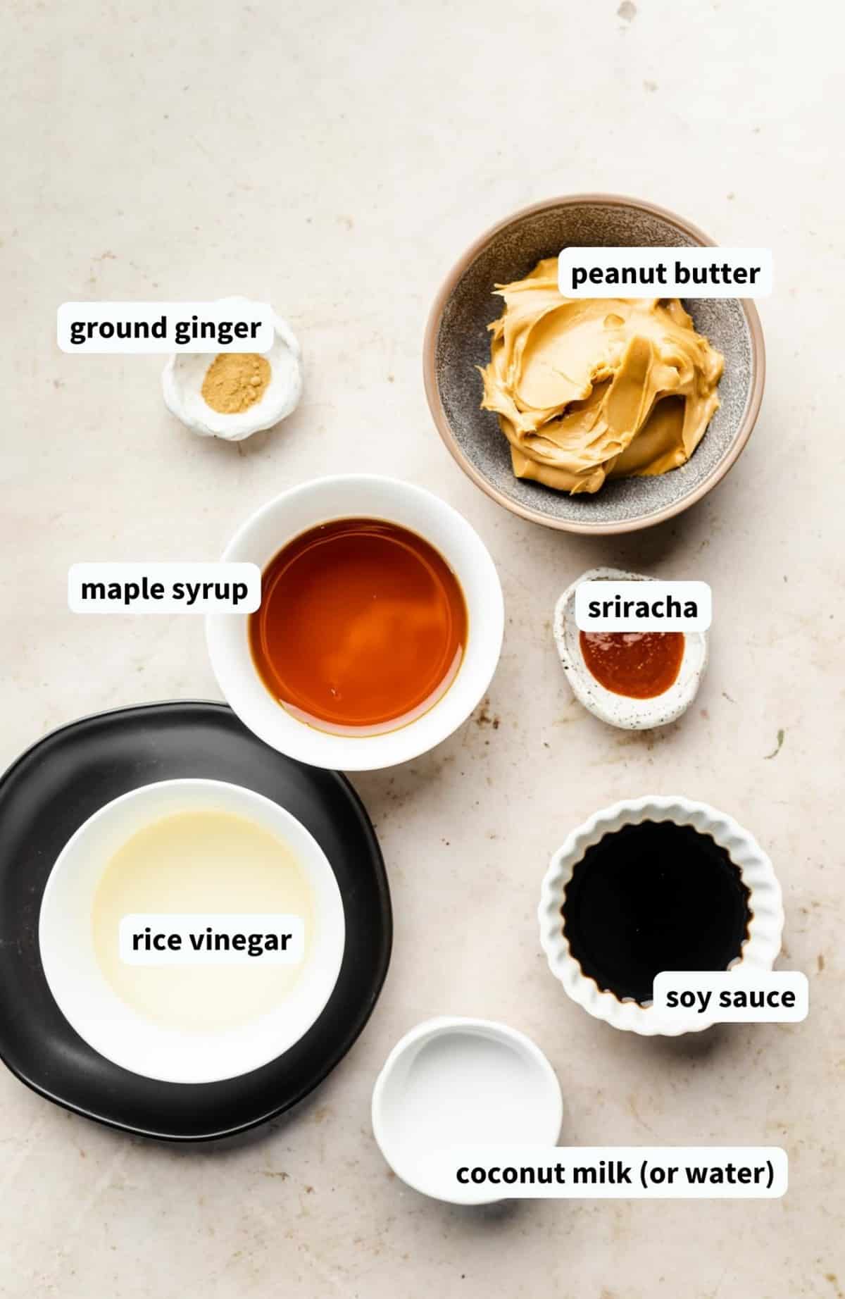 Vegan peanut sauce ingredients in separate white bowls.