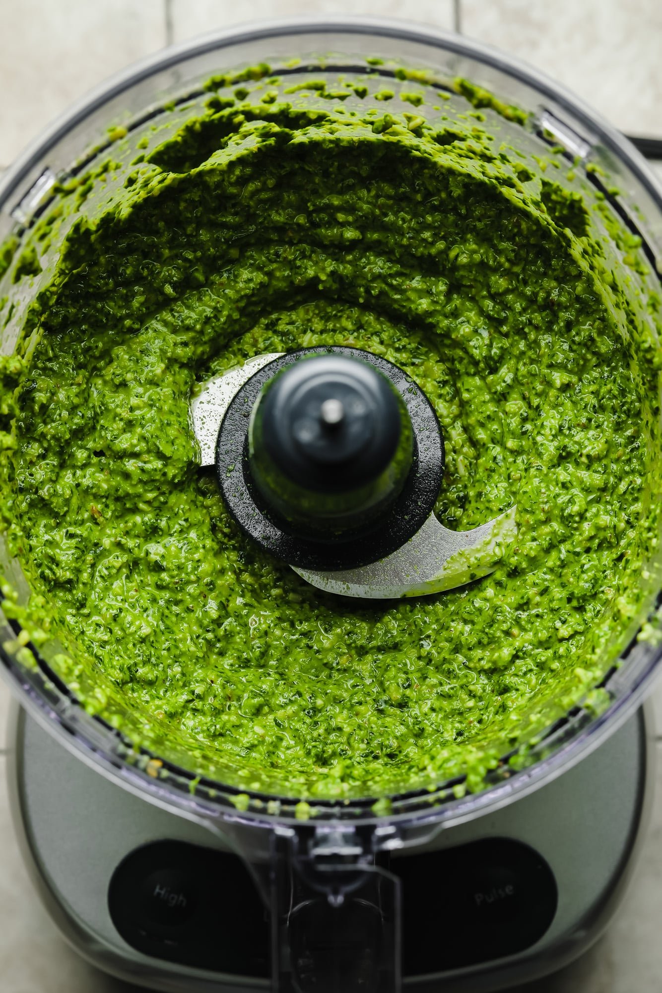 a blended batch of spinach pesto in a food processor.