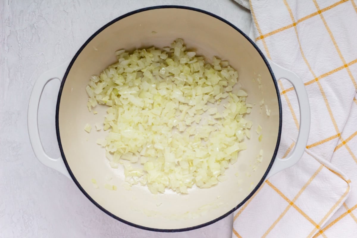 onions sauted in a white pot with yellow-white squared towel.