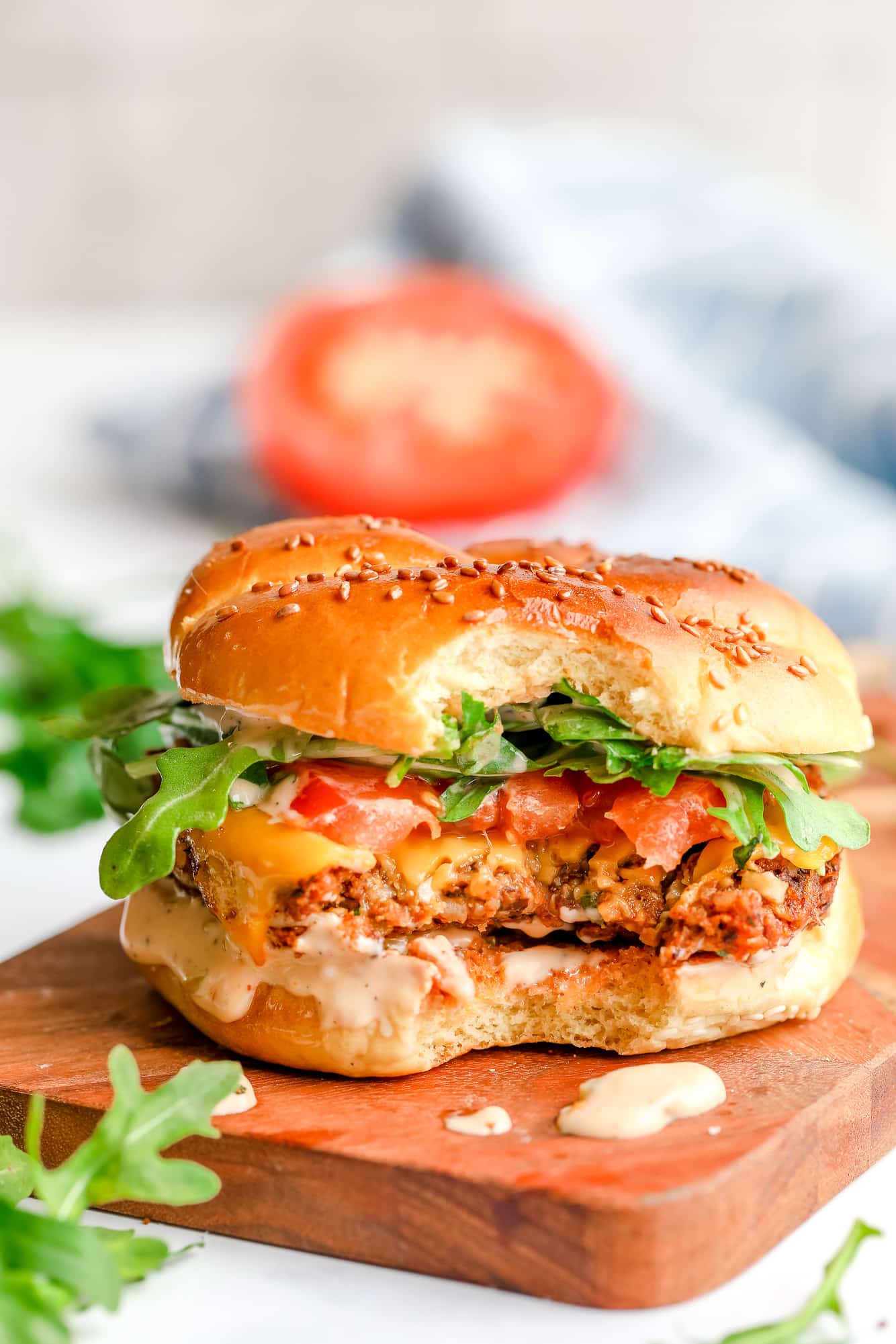 a veggie burger with a bite taken out of it on a wood board.