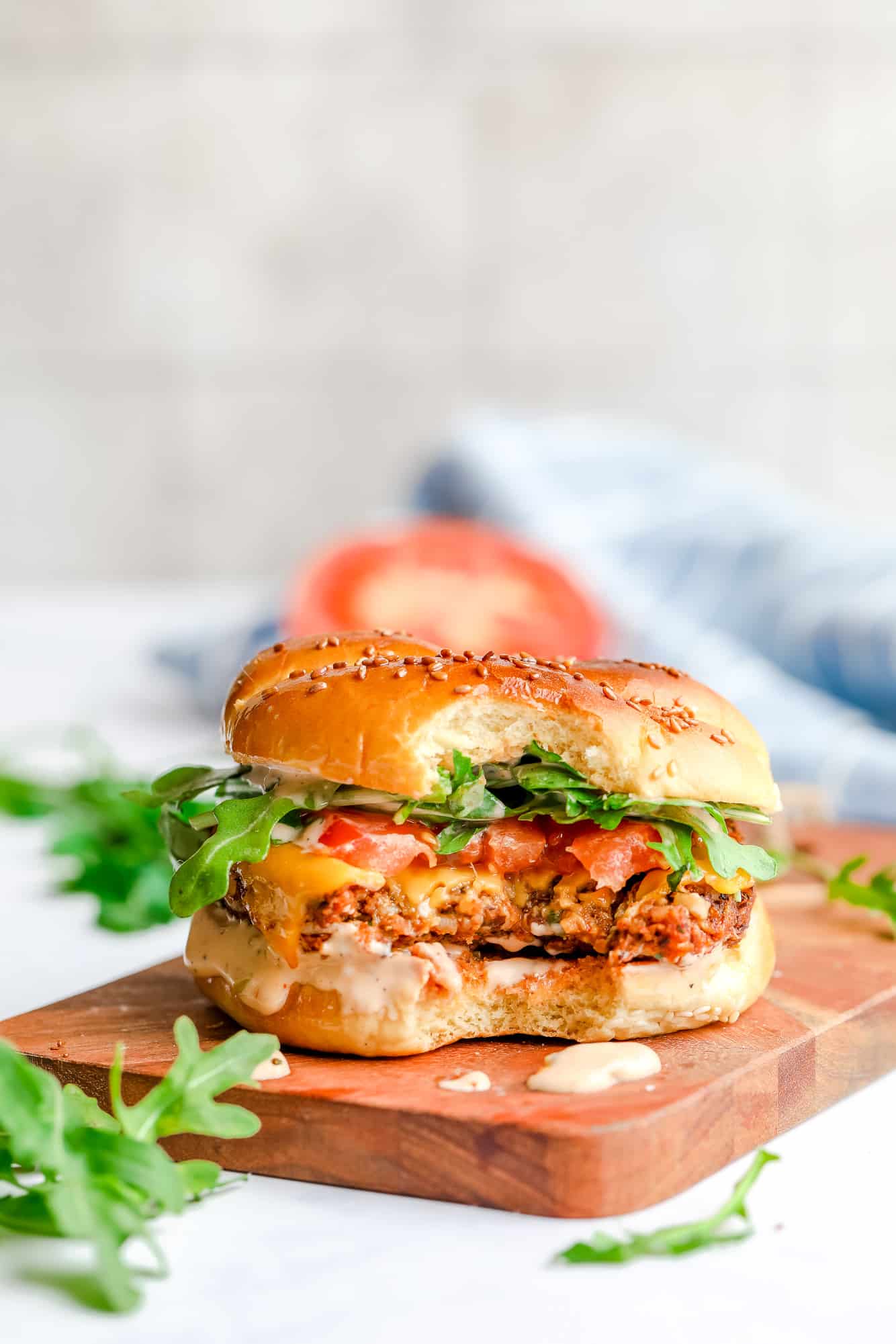 a veggie burger with a bite taken out of it on a wood board.