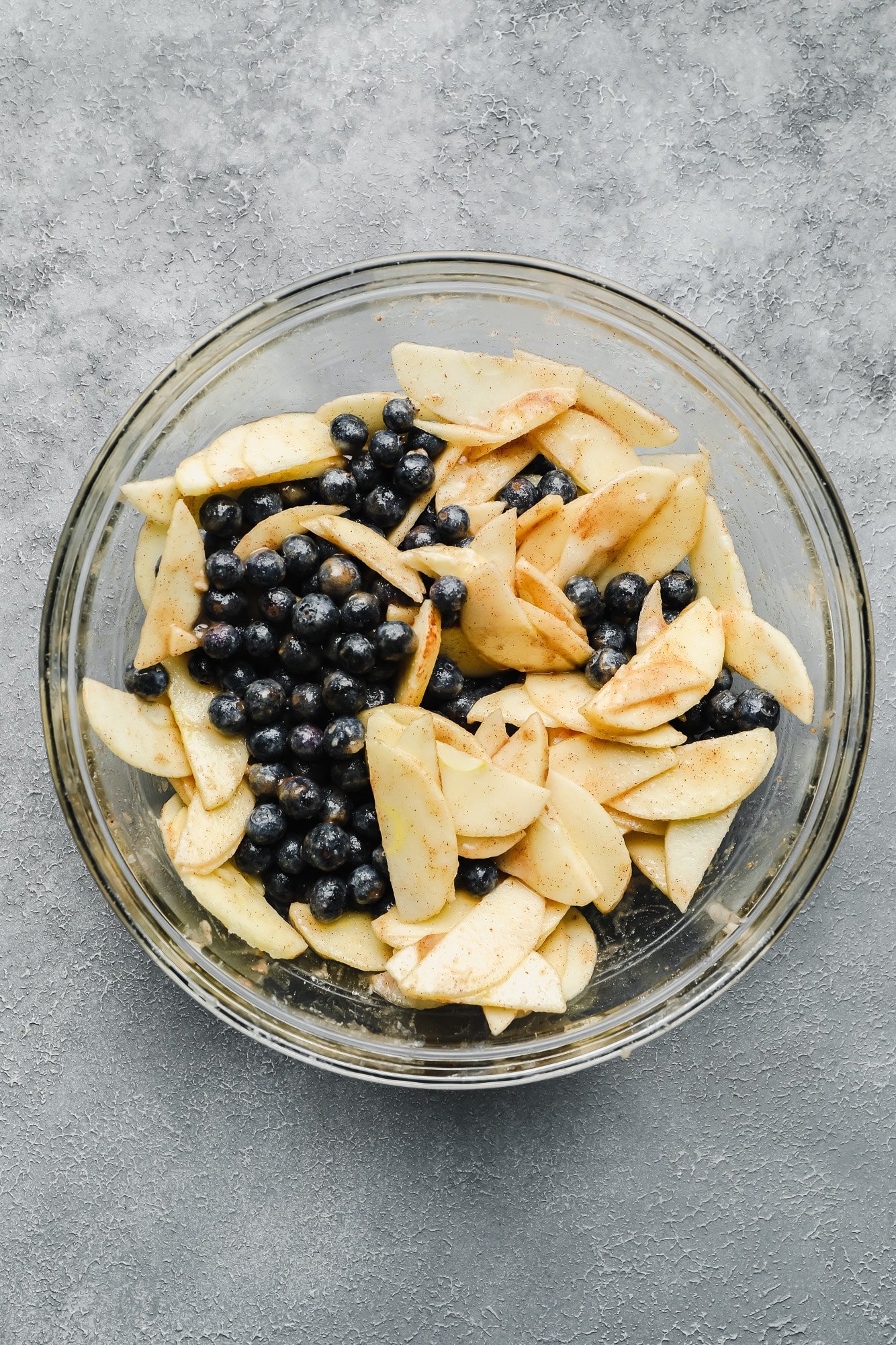 blueberries and slices apples in a glass bowl.