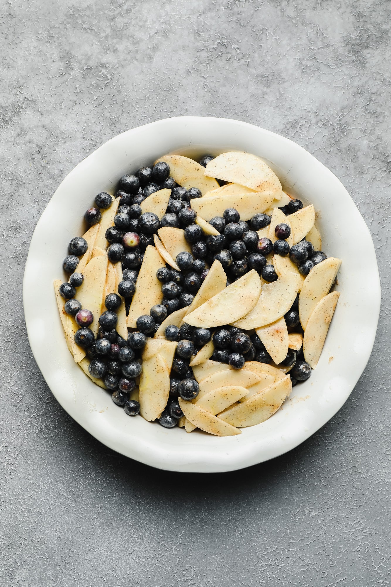 blueberries and slices apples in a white bowl.