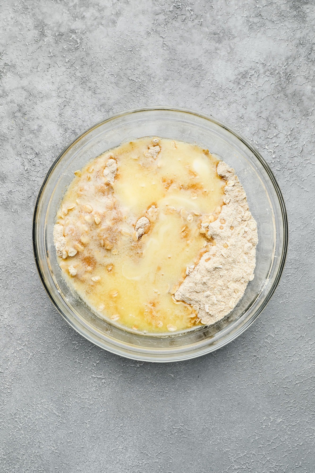 melted butter poured over flour, brown sugar, oats, and cinnamon in a glass bowl.