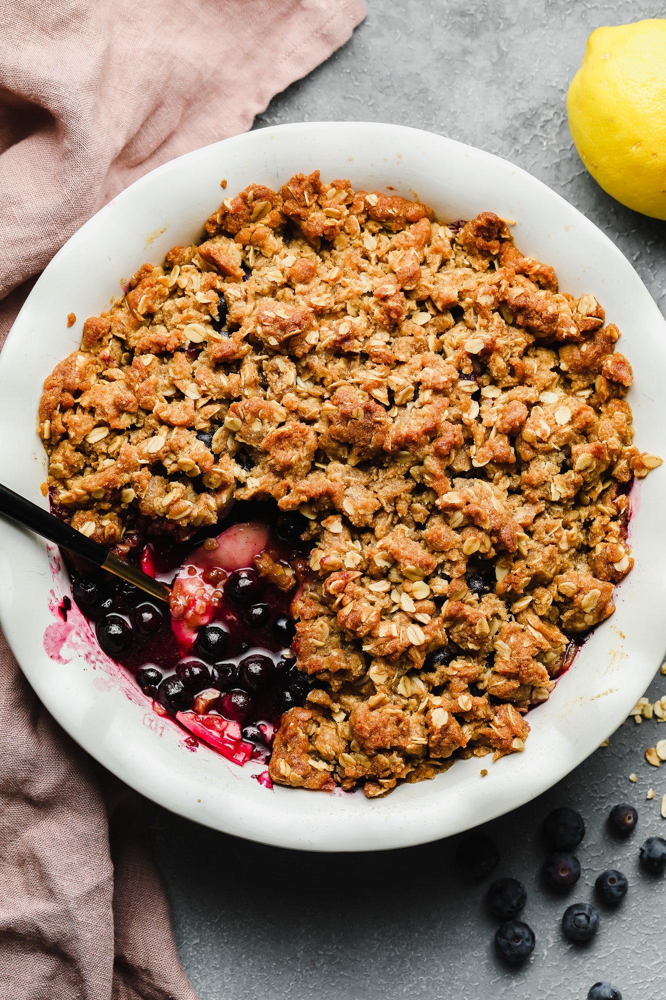 baked apple and blueberry crumble in a white bowl.