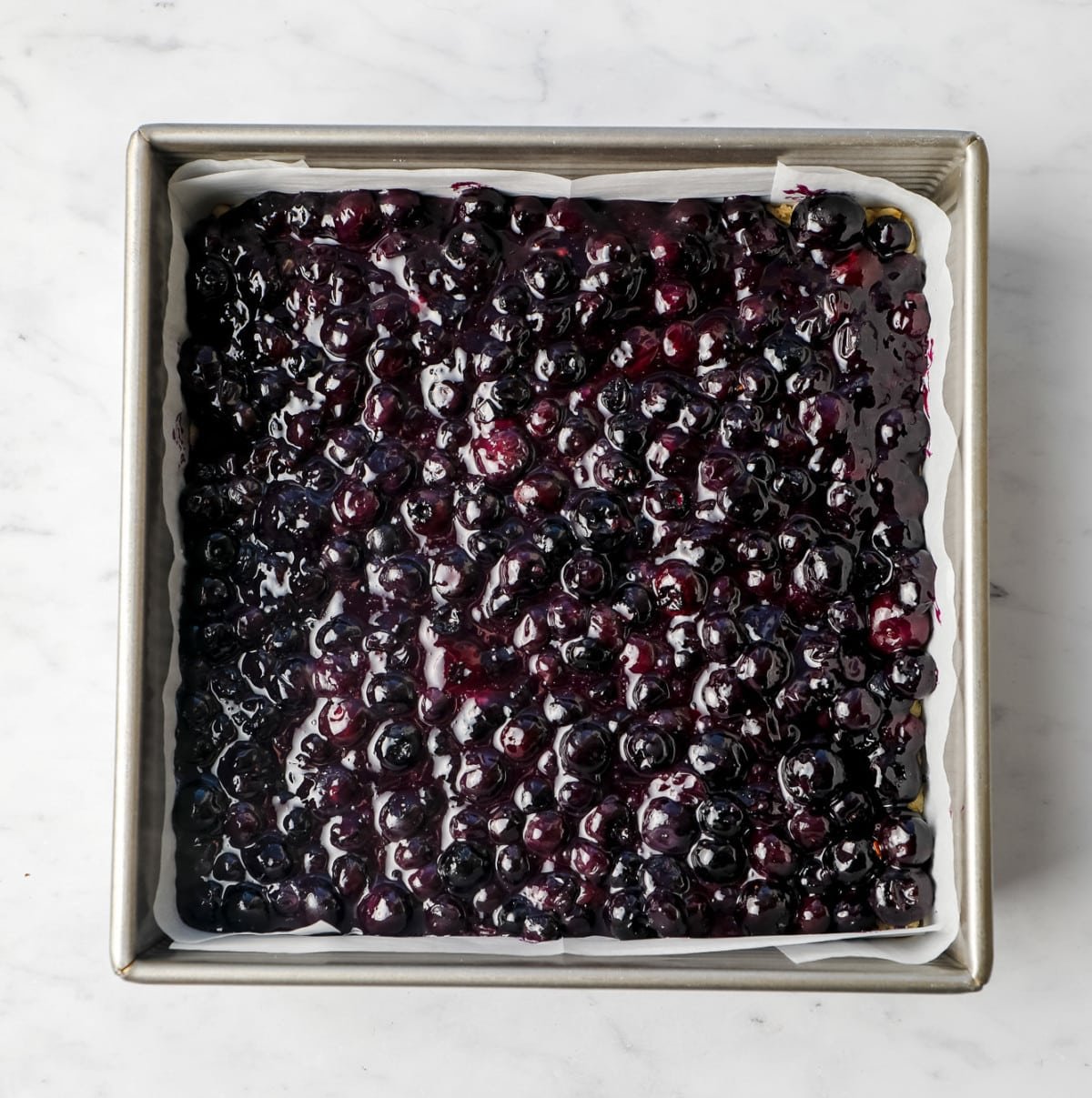 cooked blueberry mixture in a square pan lined with parchment paper